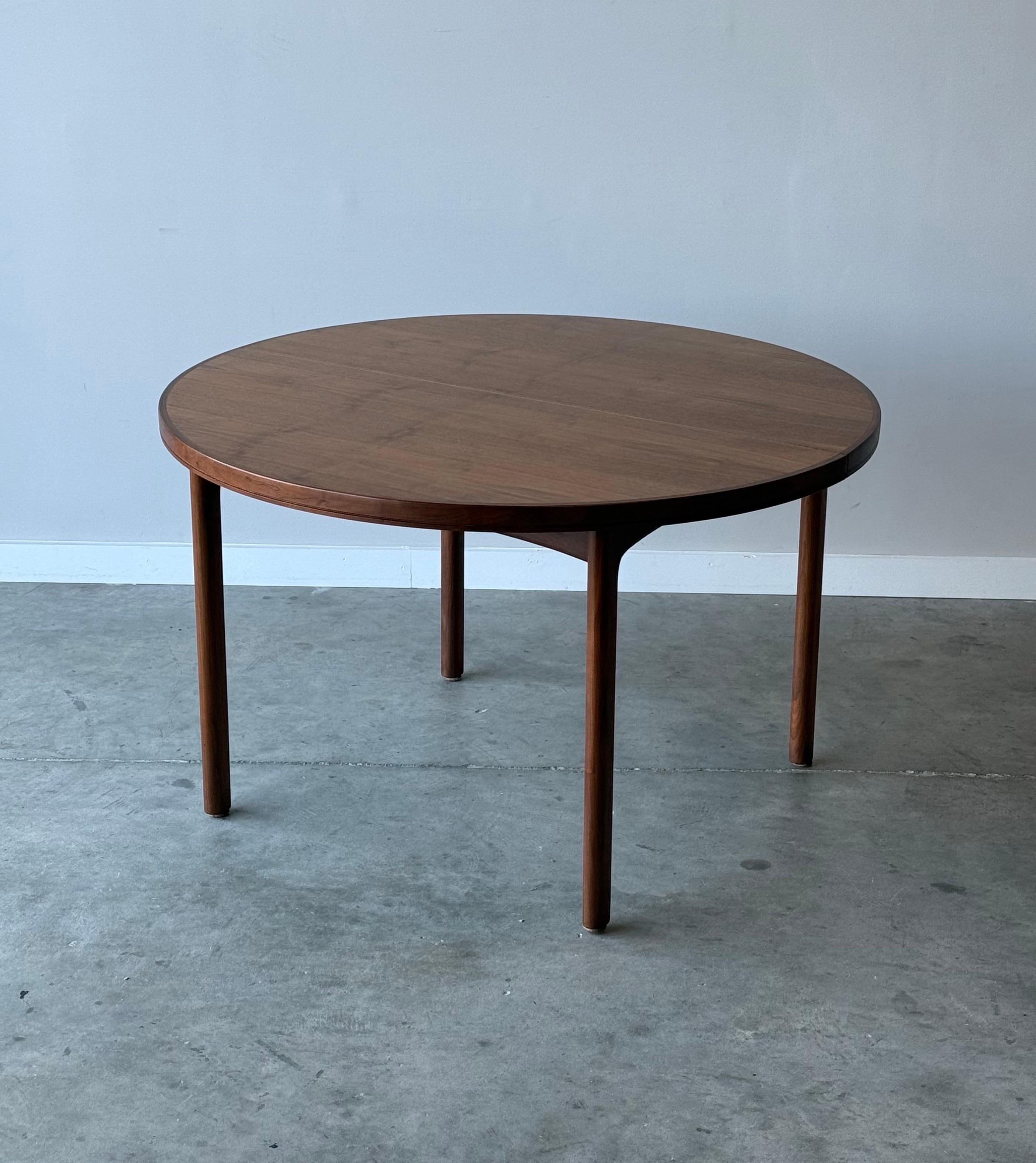 Mid-century round dining table designed by Folke Ohlsson for Dux, circa 1950s. This table is equipped with one leaf that transforms the shape from perfectly round to oval. Made from teak wood, yet warm tone, and similar to walnut. The perfect