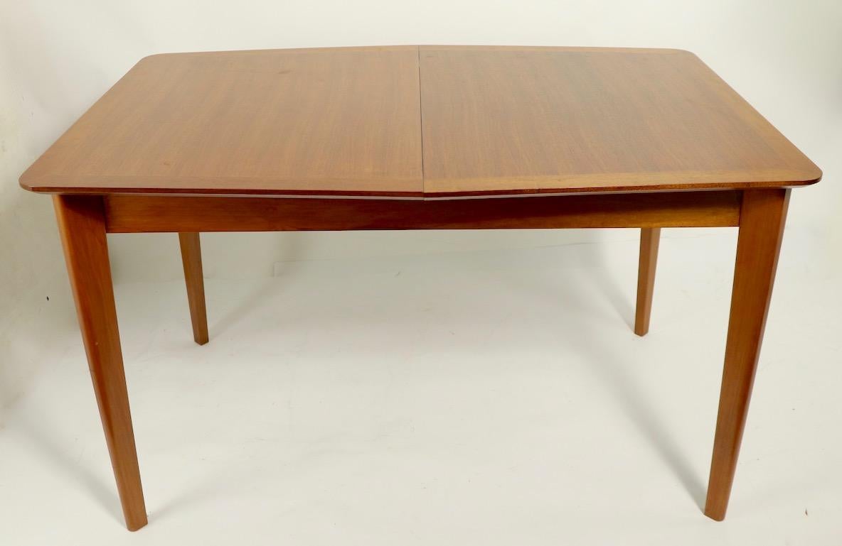 Architectural, sophisticated midcentury dining table by noted English maker Gimson and Slater, retailed by Heals of London. This chic table is asymmetrical having a six sided top which is wider in the center, tapering toward the narrow edges (32.5 -