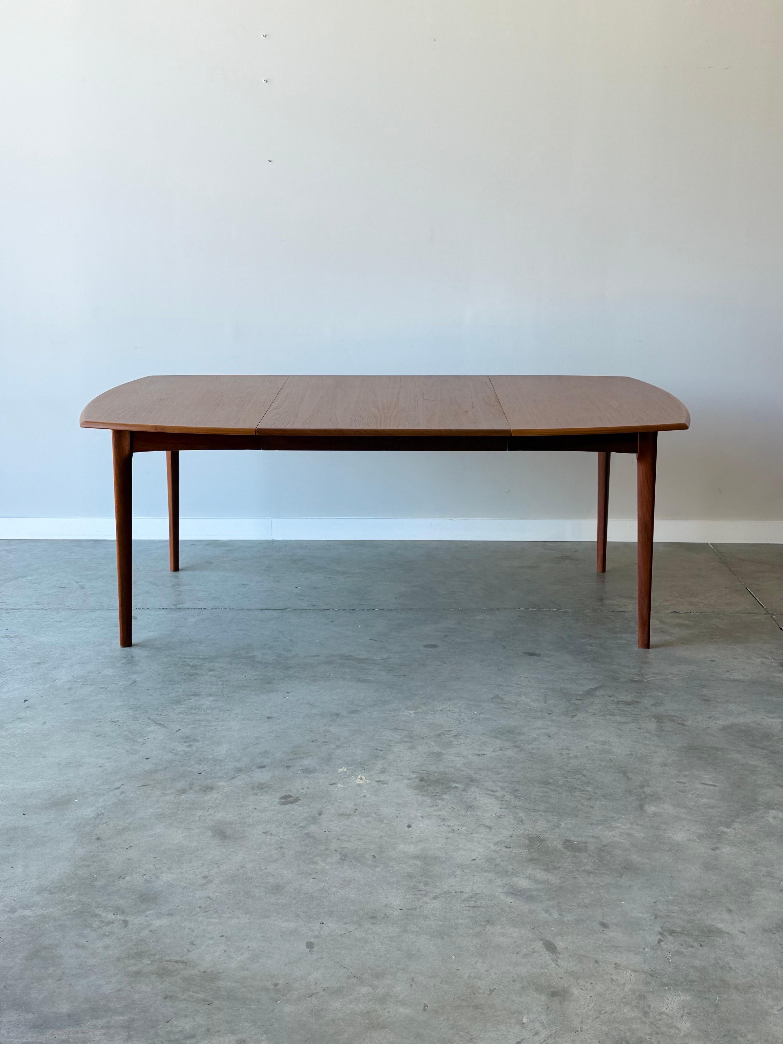 Mid-century dining table designed by H.W. Klein for Bramin Møbler, Denmark. Made from teak wood and includes large additional leaf. The table top is quite wide and long with rounded sides and corners. Square in shape without leaf and rectangular in