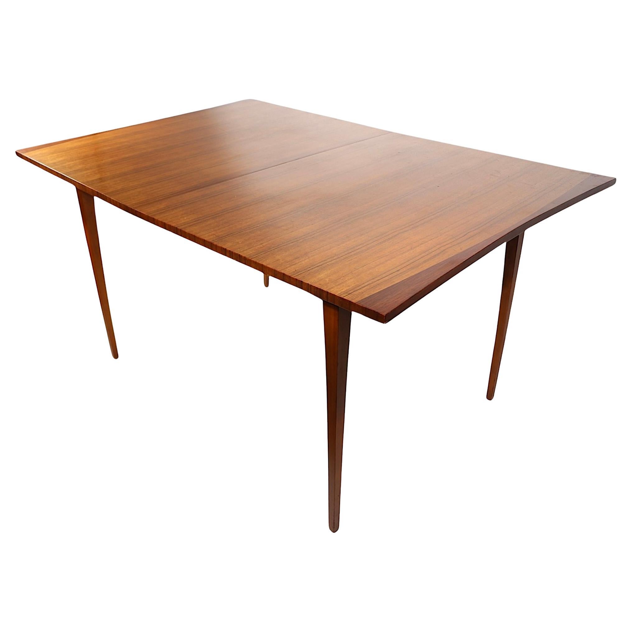 Élégante table de salle à manger à rallonge du milieu du siècle, fabriquée par Lane Furniture, dont le design est attribué à Paul McCobb. La table présente un plateau de forme sculpturale en placage de bois exotique bicolore. La table s'ouvre pour