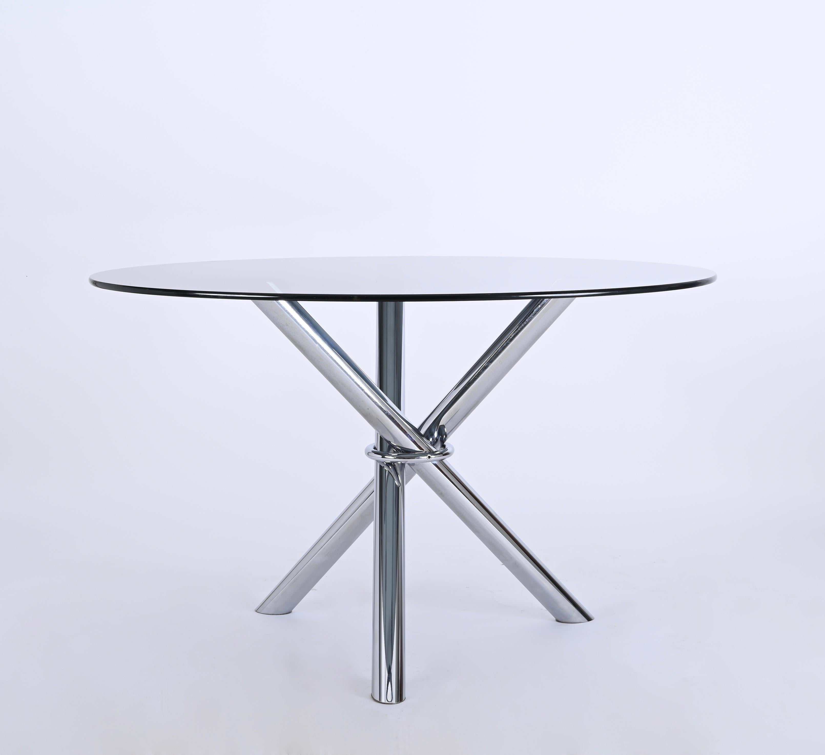 Beautiful dining table in chromed stainless steel with smoked glass top, it was designed in Italy during 1970s.

The base of this enchanting dining table features three chromed legs kept together by a chromed ring, resulting in an ethereal yet