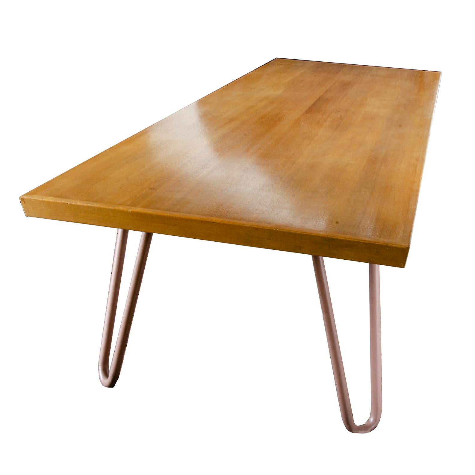 This large midcentury table is grand enough for a conference table, but could definitely do a fine job in any dining room. Four hairpin style legs in stout proportions jut out from the solid maple top. The clean silhouette would blend seamlessly in