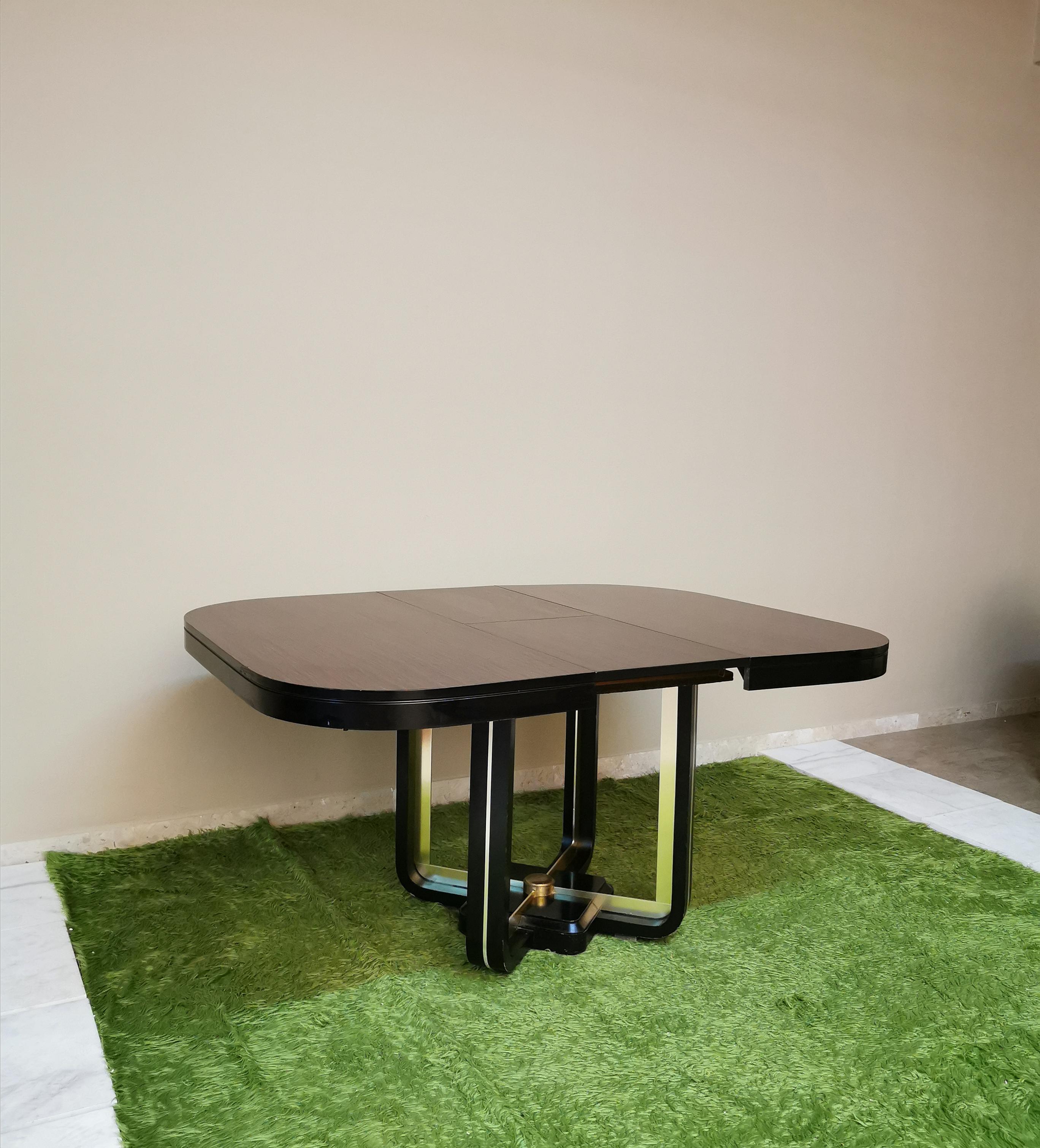 Dining table with foot in black lacquered wood, accessories in golden aluminum that support an extendable top in square mahogany wood with rounded corners. Italian production of the 70s.