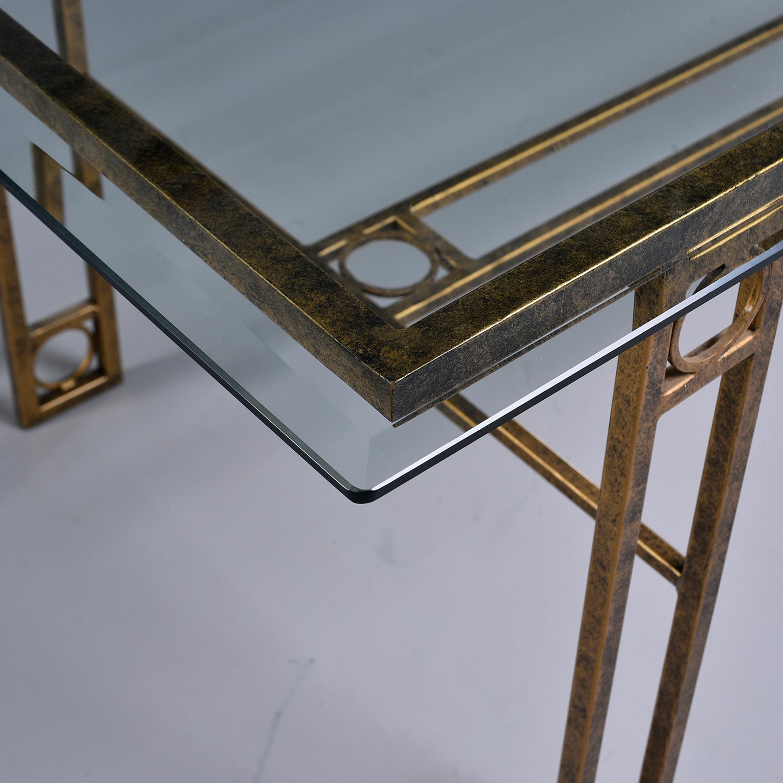 Dining table has an iron base with a burnished gold finish and open work design of rectangles and circles. Rectangular glass top has beveled edge and is in very good vintage condition. Unknown maker. Found in England, circa 1970s.