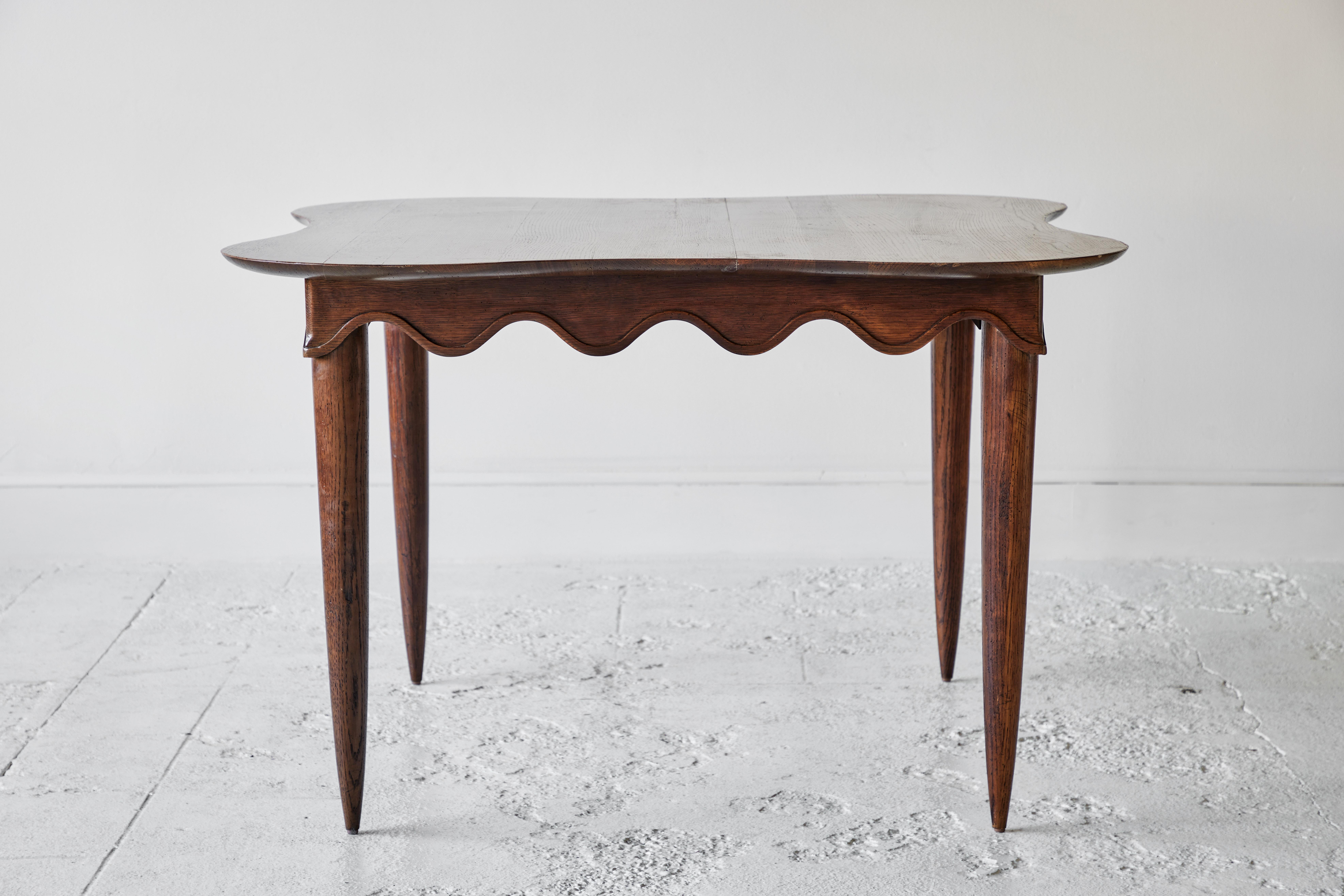 Midcentury dining table with scalloped apron and tapered legs.