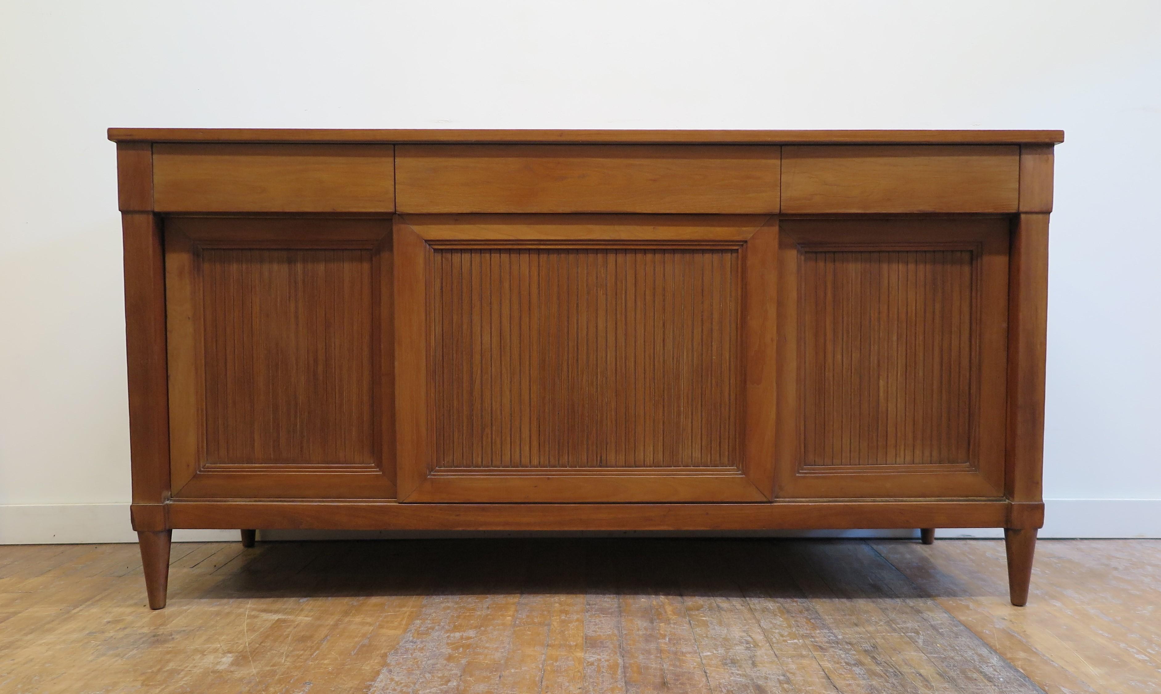 Mid century classic directorie styled credenza sideboard. A Classic styled credenza having modern directorie styling incorporated into the clean lines. Made in the late 1950's of Cherry wood and veneers. Very functional having three drawers across