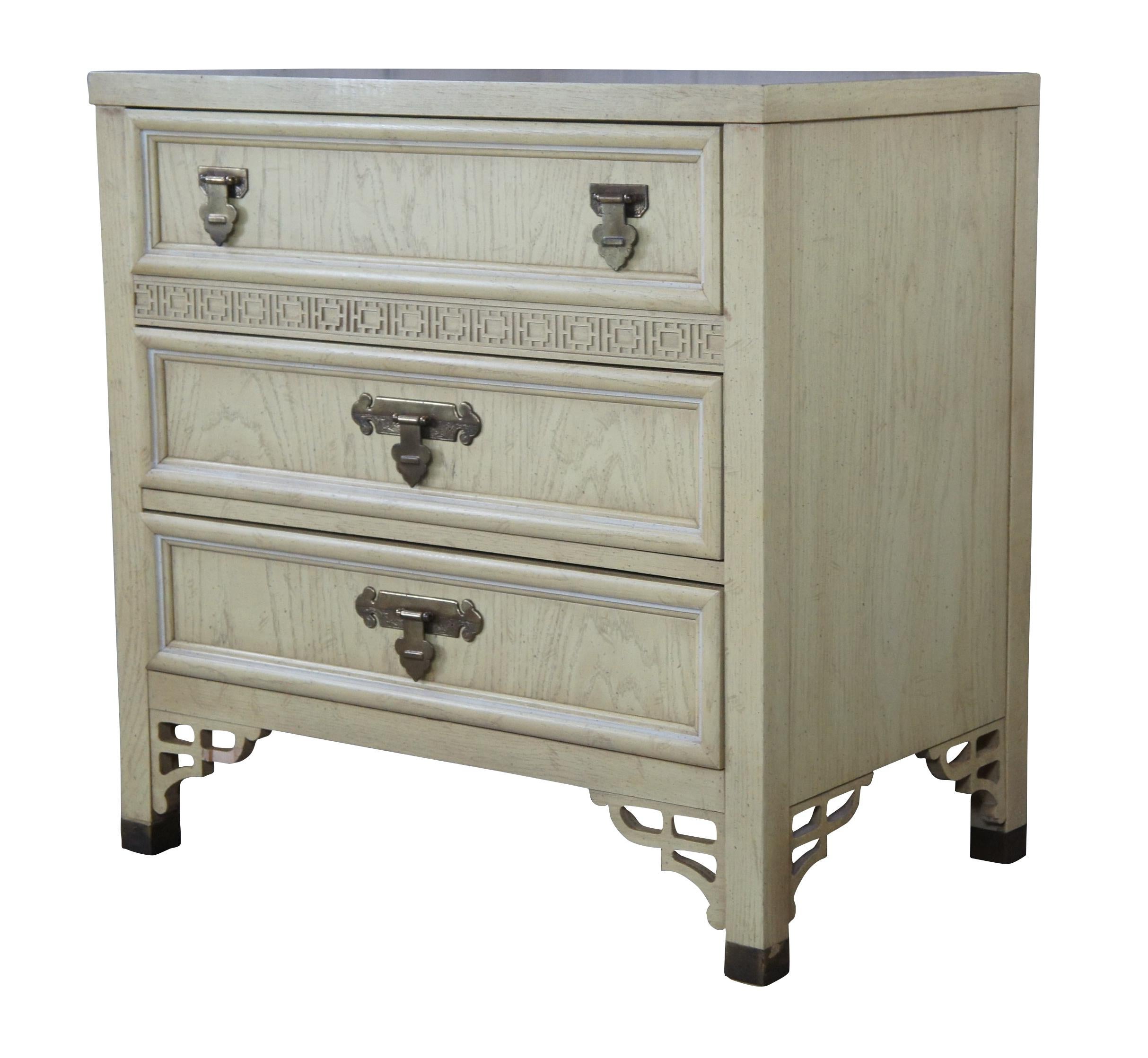 Mid-20th century pickled oak Campaign chest of drawers by Dixie. Part of their Shangri La chinoiserie collection. Features three dovetailed drawers, fretwork and brass hardware. Naturally distressed. Marked Bachelor Chest 322-513 along the back.