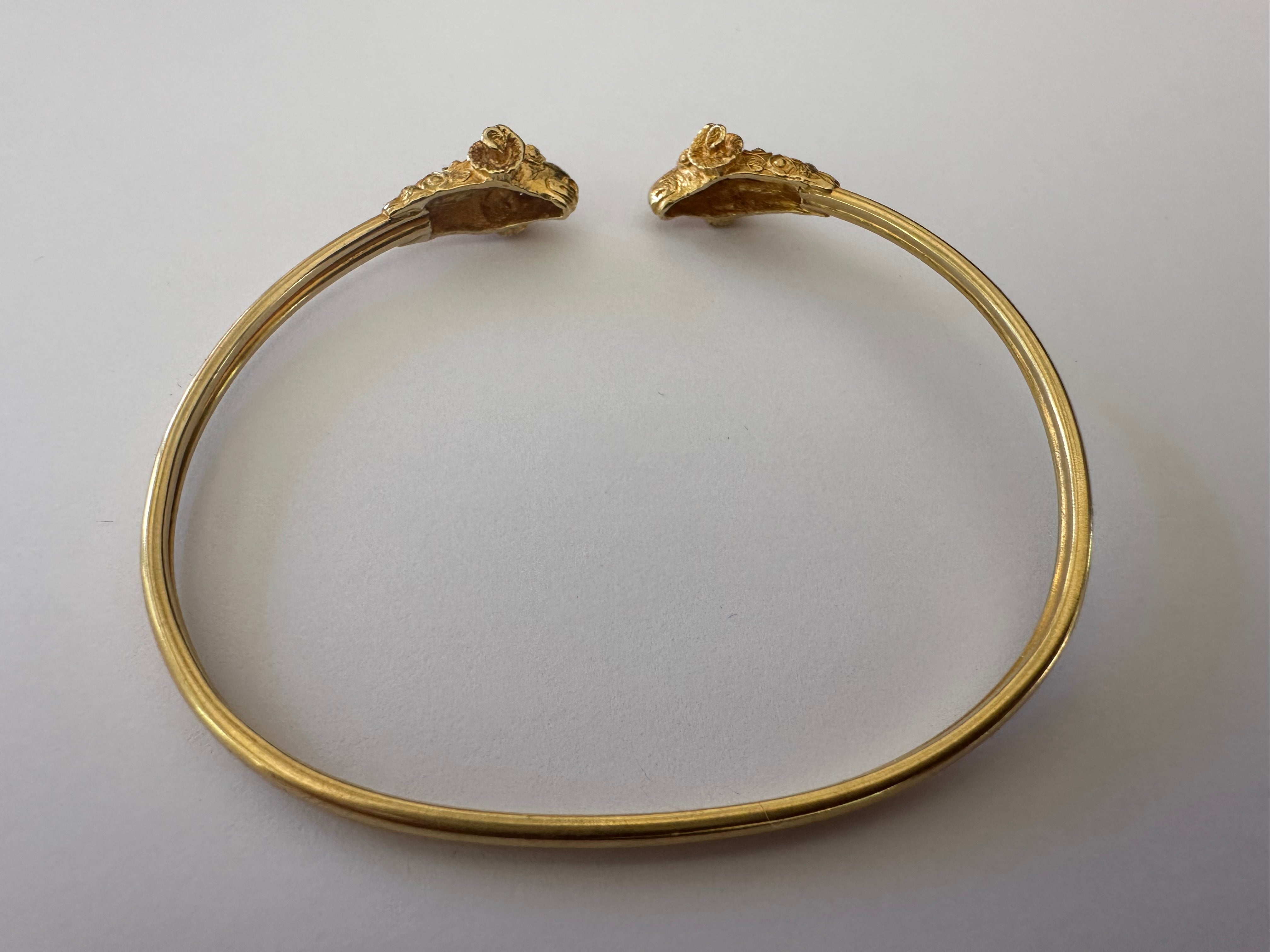 Questa rappresentazione dorata del magnifico ariete, spesso associato alla forza nella mitologia greca, è scolpita in modo squisito in questo braccialetto bangle flessibile con una doppia testa di ariete realizzata in oro giallo 18 carati. Circa