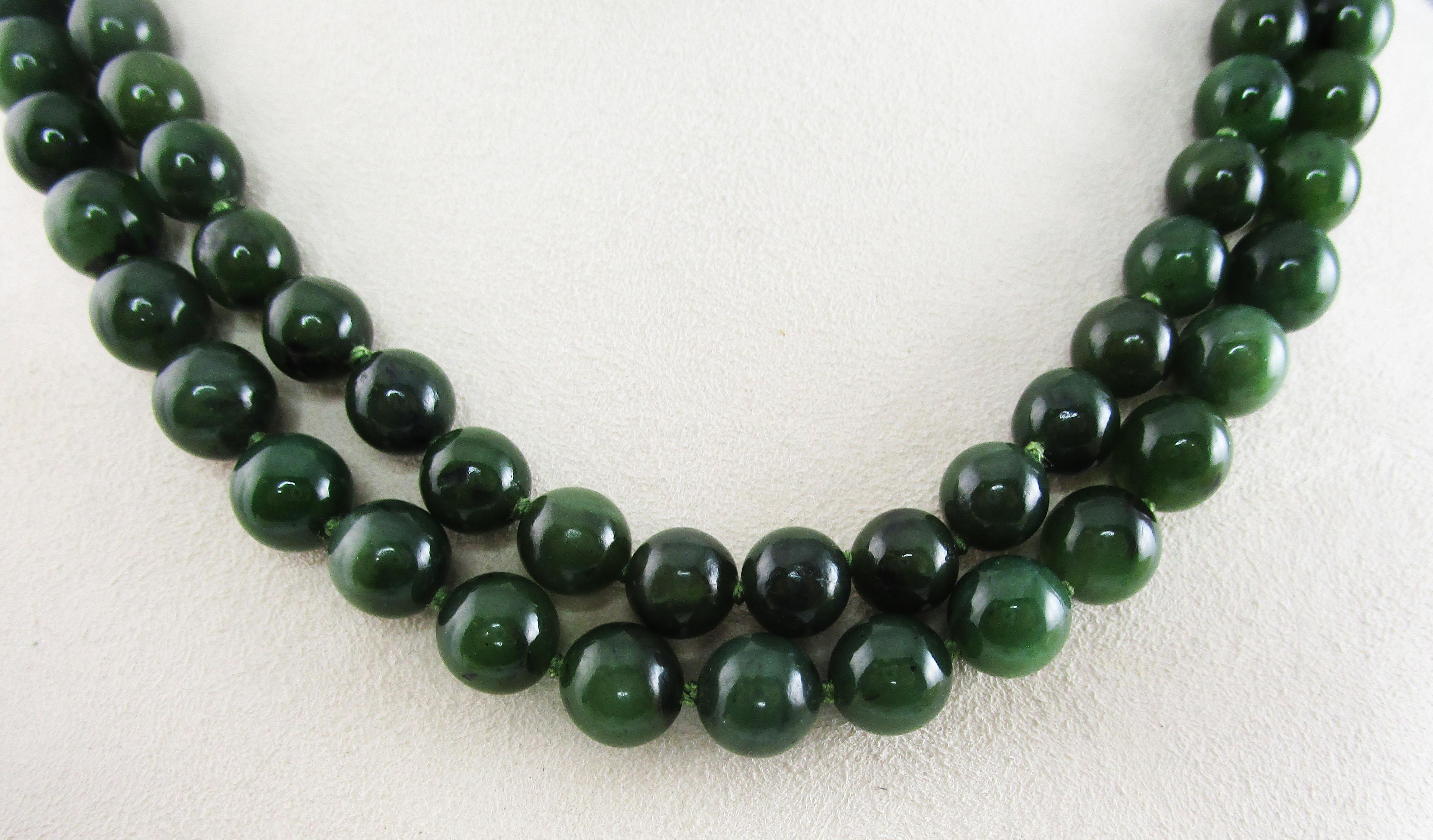 This is an absolutely remarkable mid-century necklace featuring a double strand of fine jade beads and a stunning 14k yellow gold clasp set with a dramatic jade cabochon! The jade of these beads is a deep forest green that has an excellent shine and