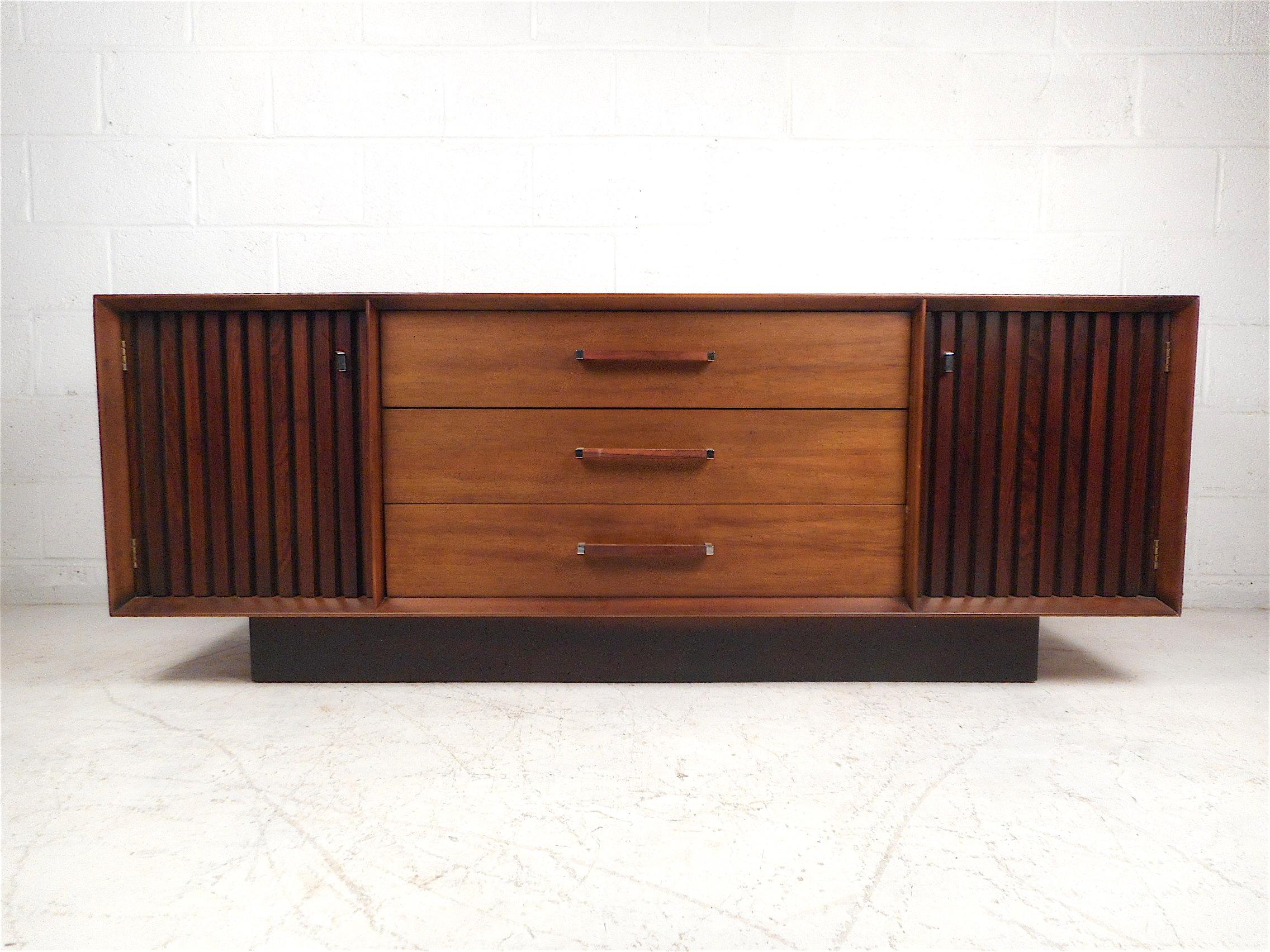 Impressive set of midcentury bedroom furniture including a long dresser and two nightstands, made by Lane Furniture Company, circa 1963. Dresser has three spacious drawers (the uppermost of which is partitioned) flanked by two storage cabinets. All