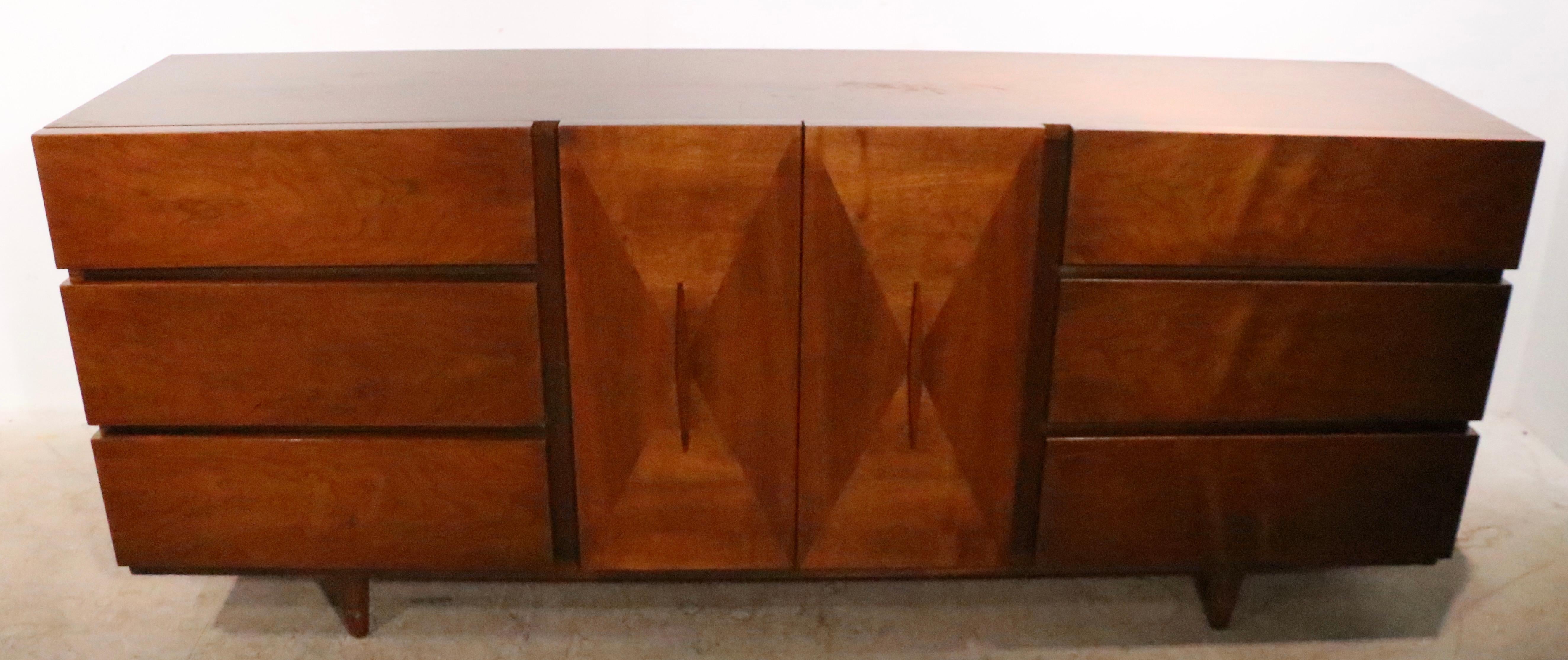Classic Mid-Century Modern dresser by American of Martinsville, design attributed to Merton Gershun. This exceptional example features three banks of drawers that flank the two door center, which opens to reveal three interior drawers. The center