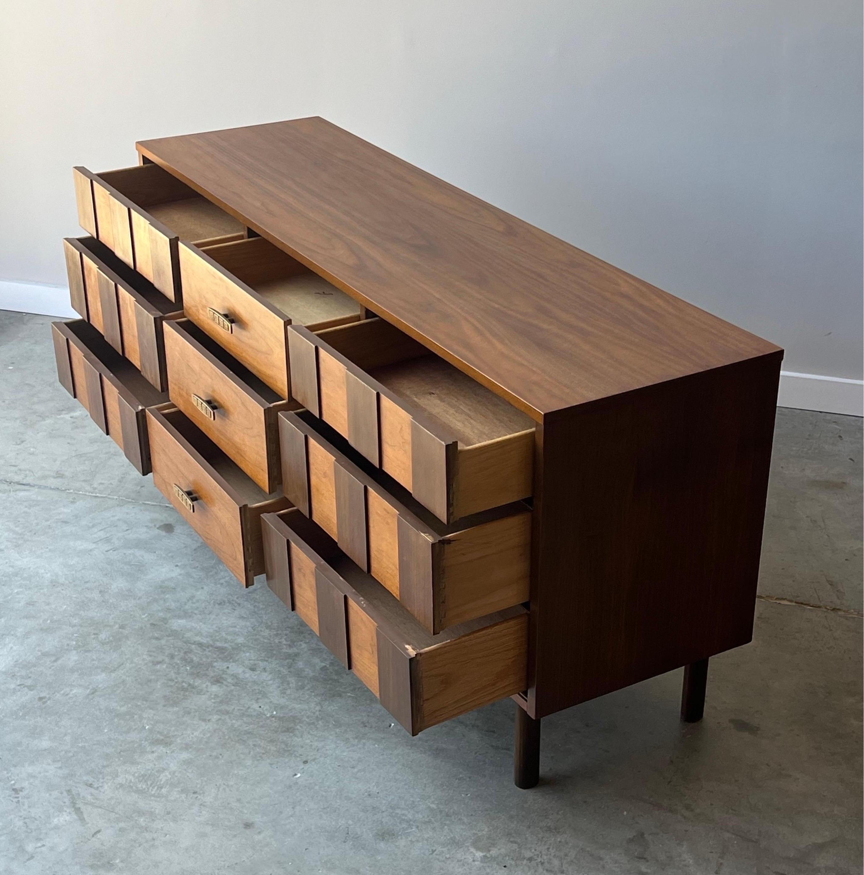 Vintage walnut dresser manufactured by Bassett, circa 1960s. This piece features nine drawers with striped design on both the left and right side. The striped effect is created by darker wood tiles atop the golden walnut. The left and right hand