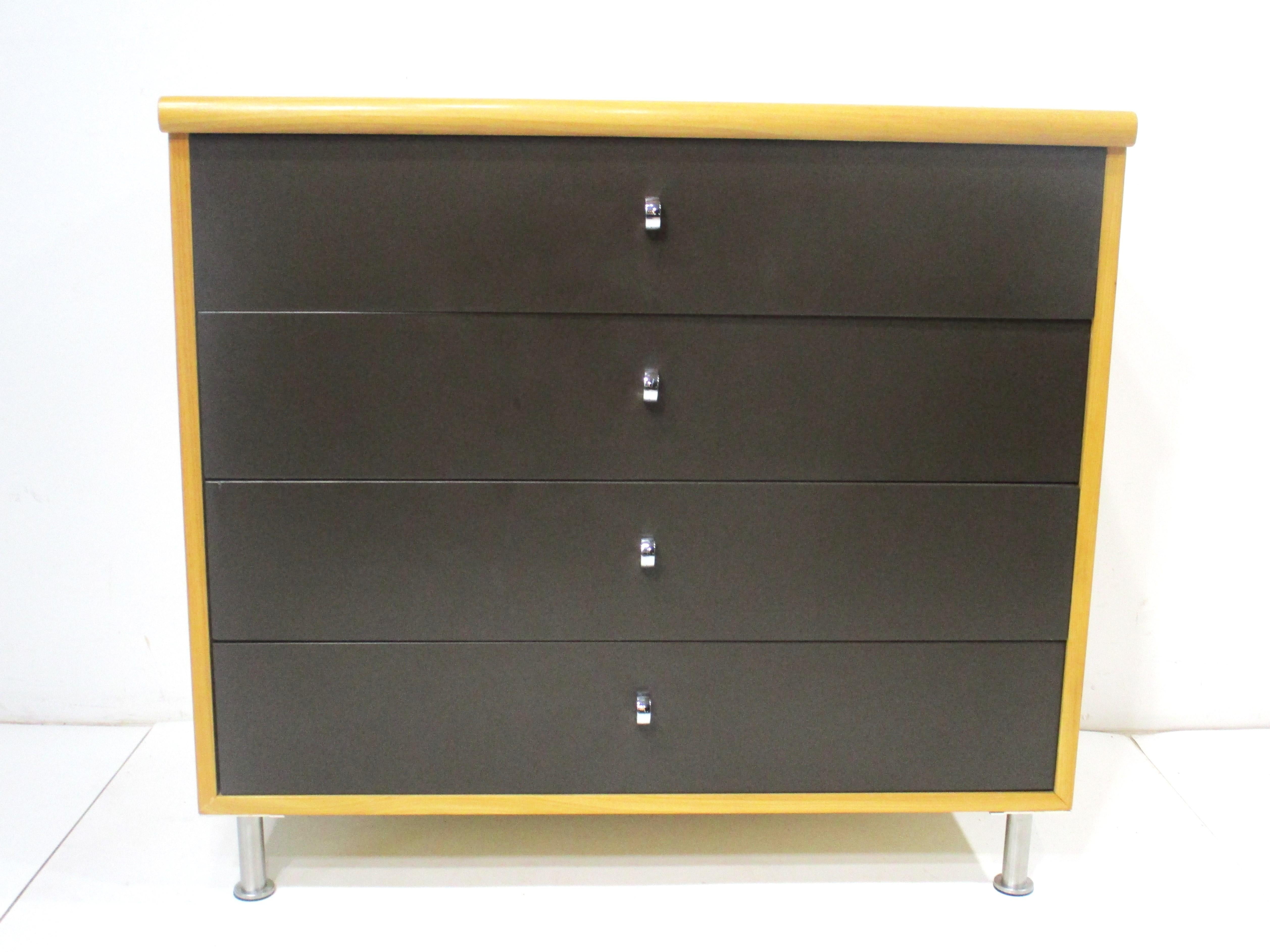 A Mid Century four drawer dresser in a very well grained clear birch with dark chocolate brown drawer fronts . The chromed U shaped finger pulls give detail to the dark color and with brushed stainless steel adjustable legs . This small scale
