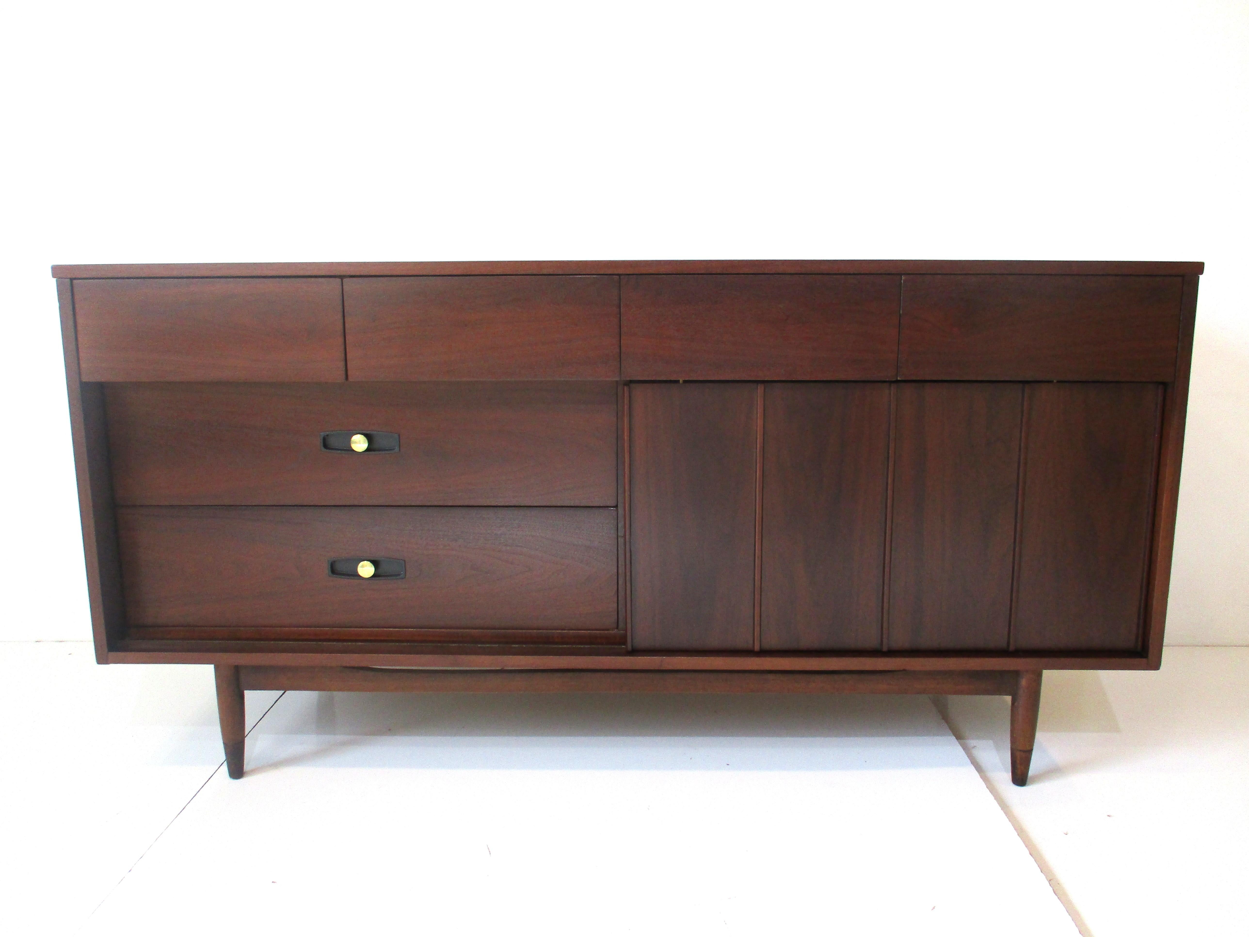 A dark walnut dresser credenza with plenty of storage having four smaller upper drawers. To one side theres four drawers and to the other two larger ones with a sliding panel in front which can be placed to ether end of the piece. Retains the