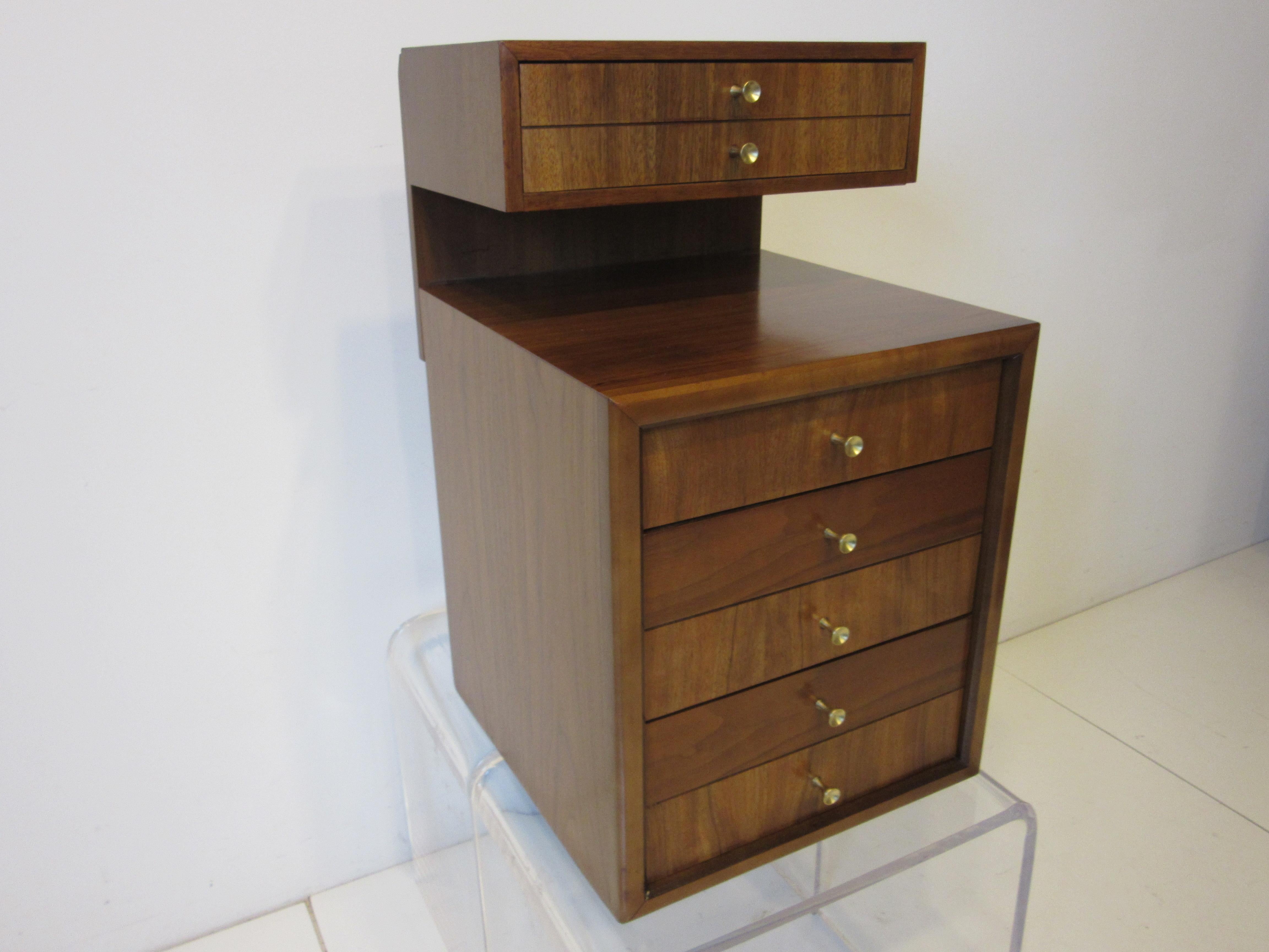 A four drawer jewelry chest / box with upper and lower storage having an area between the two for laying out your pieces to try on. The medium dark walnut with fine graining and the brass pulls give the chest a rich look for placement on a dresser,