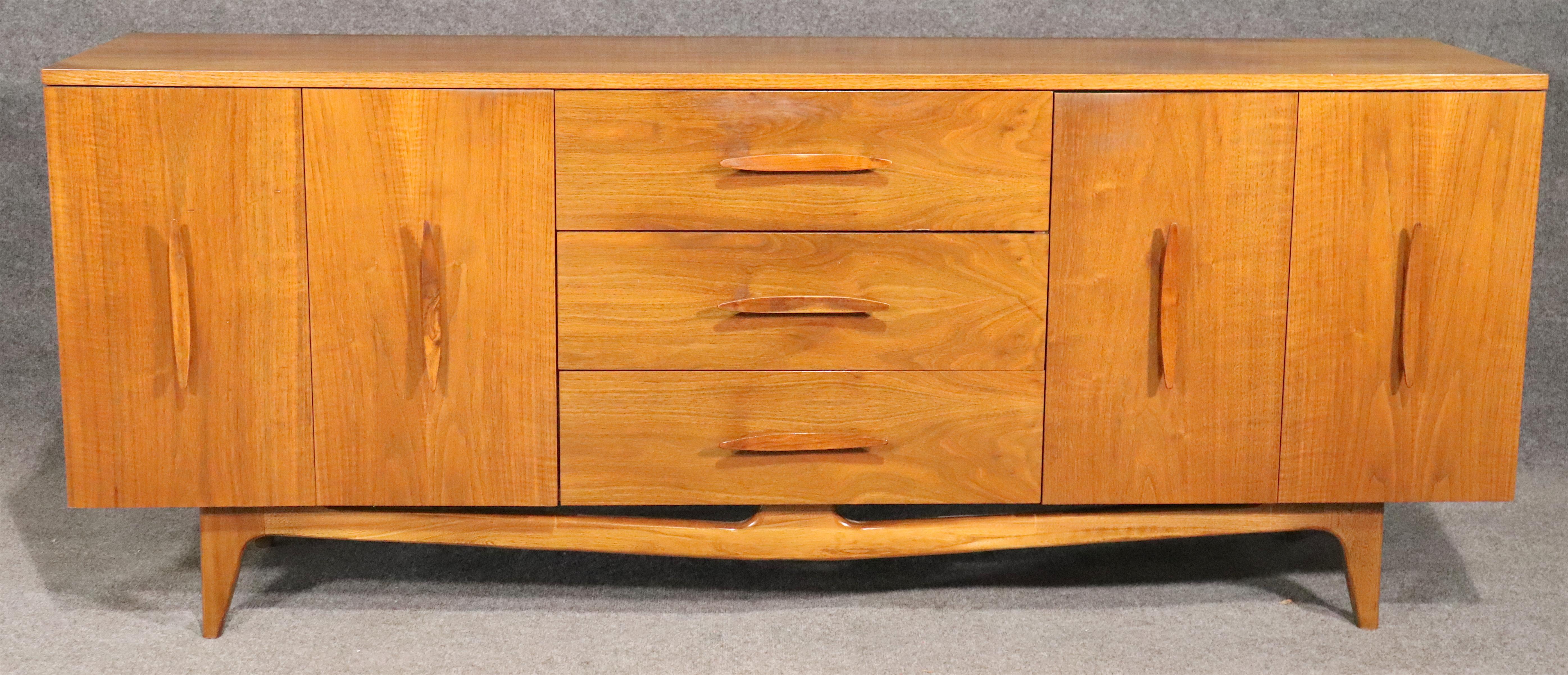 Long Mid-Century Modern American dresser with warm walnut grain and curved wood handles. Nine wide drawers offer ample bedroom storage.
Please confirm location.