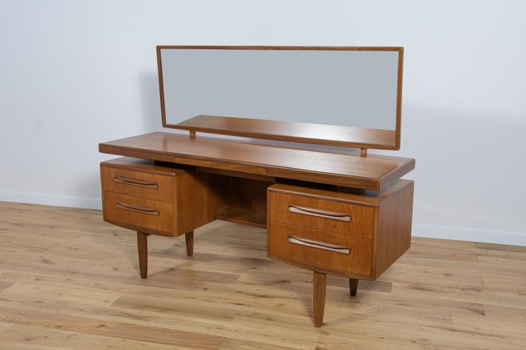A teak dressing table designed by Victor Wilkins for the British manufacture G-Plan from the 1960s. In the middle there is a small, discreet drawer for jewelry. There is an adjustable mirror above the dressing table. Old surface have been