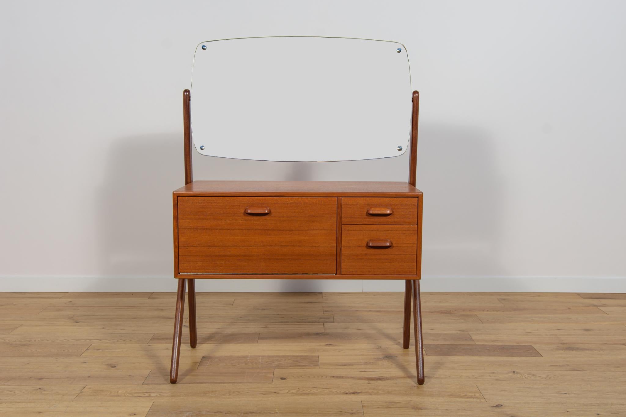 A small teak dressing table produced in the Danish factory Ølholm Møbelfabrik in the 1960s. It consists of two drawers and an opening cabinet. There is an adjustable mirror above. The furniture has been completely renovated, cleaned of old coating