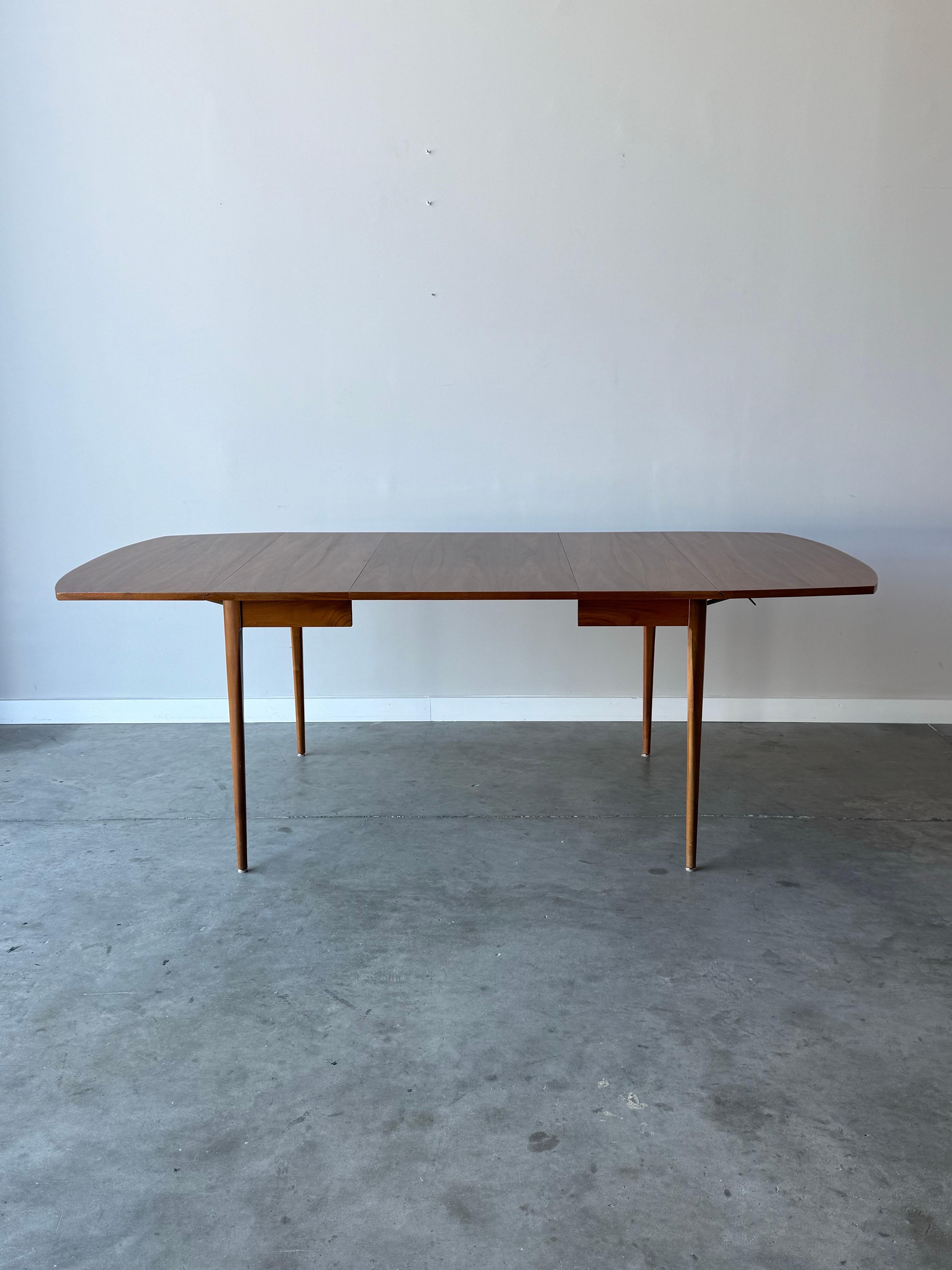 Table de salle à manger du milieu du siècle conçue par Kipp Stewart pour Drexel. Cette table fait partie de la ligne emblématique Declaration de Drexel. Fabriquée en riche bois de noyer, la table est ornée d'un fantastique grain de bois. Un abattant