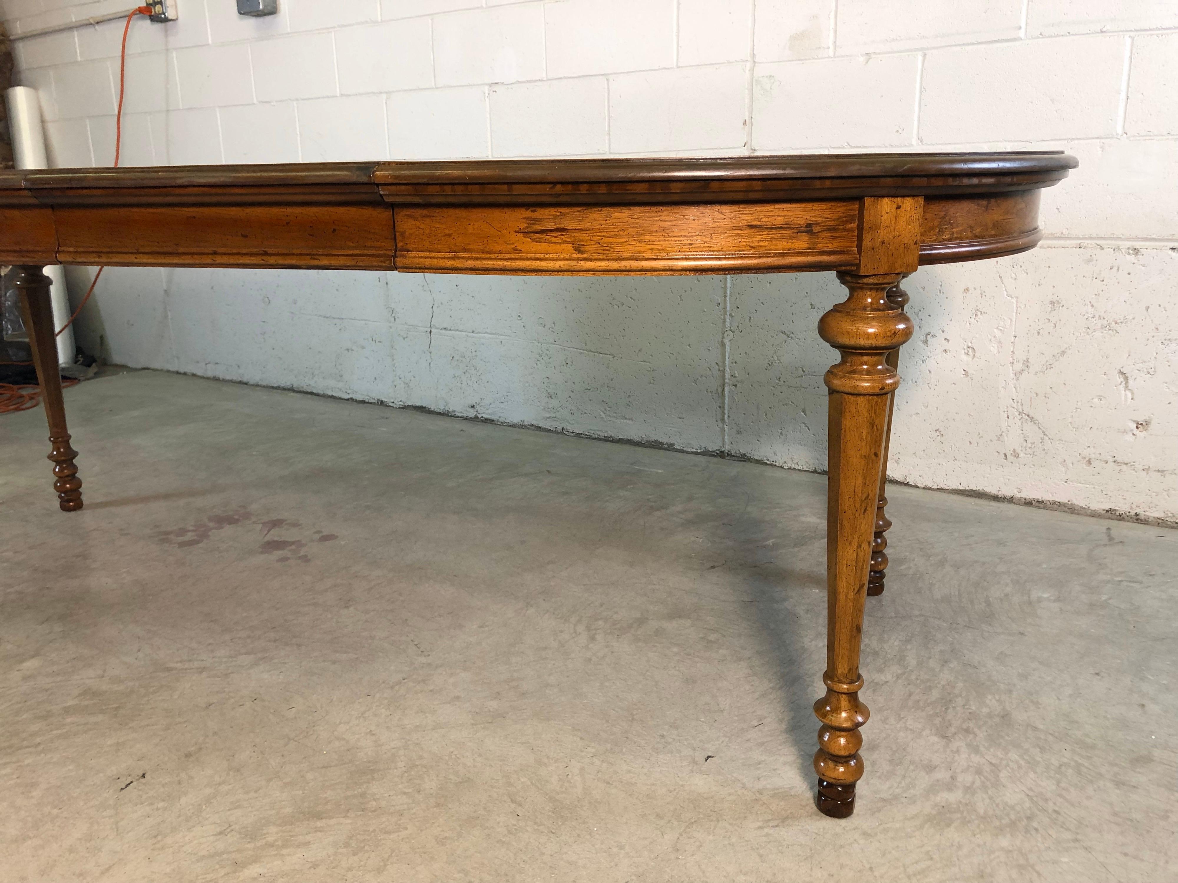Midcentury 1960s Drexel Furniture dining room table from the Velero line. The oval top table has a diamond matched design with two center extension leaves. The legs are nicely turned for a simple yet elegant design. The table fully open is 92.5” L.