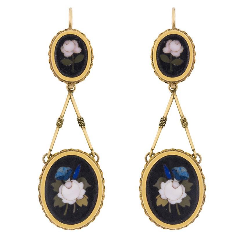 This pair of earrings and its matching brooch originated in the 1950s/60s. These mid-century drop earrings for pierced ears feature an oval-shaped, gold-framed inlay of a rose, which has been fitted with an inverted V-shaped extension leading to a