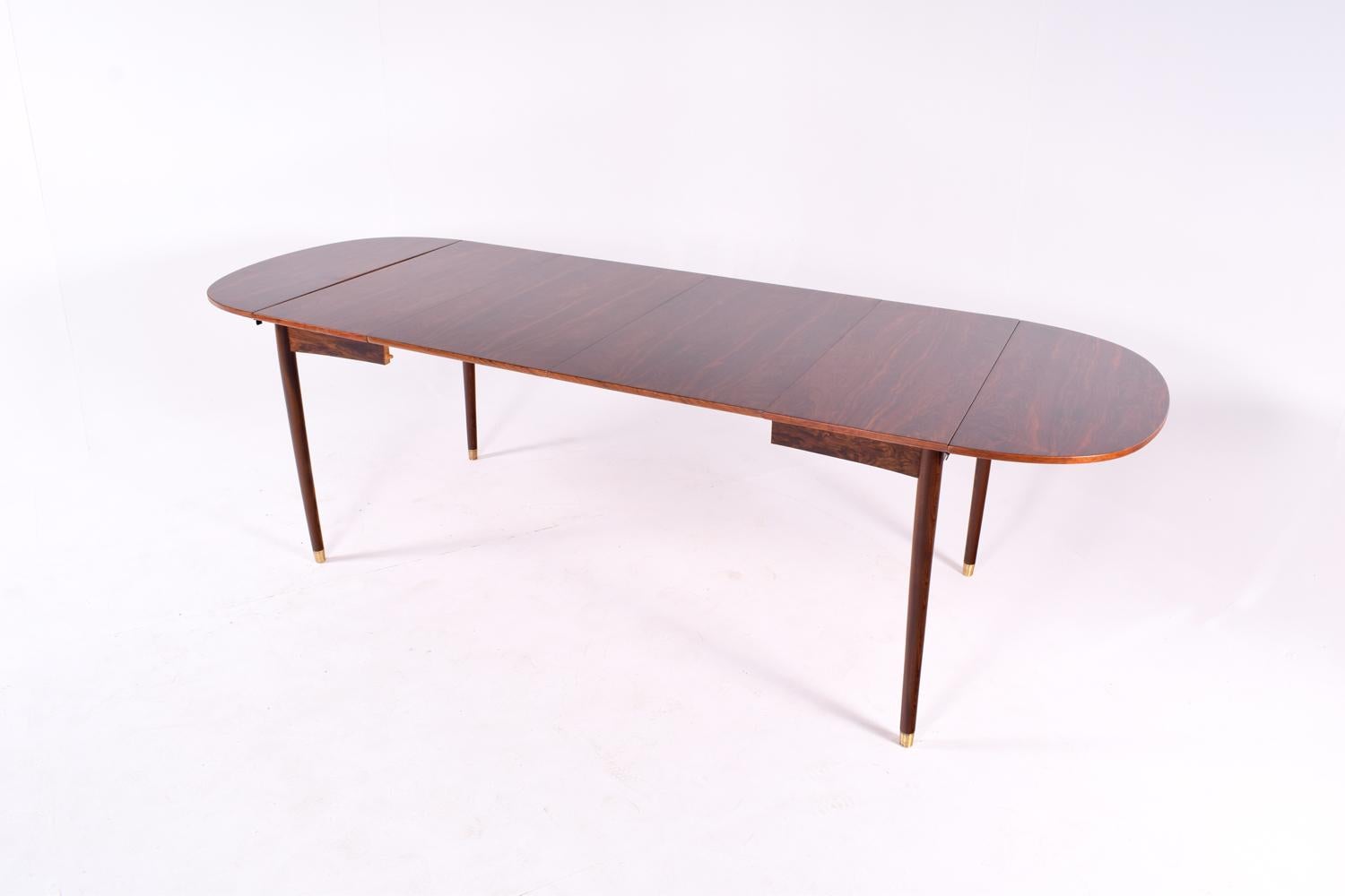 Danish modern rosewood drop-leaf extension dining table. Table has 2 ends that drop down with 38 cm each to the sides along with 2 removable 50 cm leaves. Elegant and appealing rosewood veneer, leaf draw matching between all leaves.