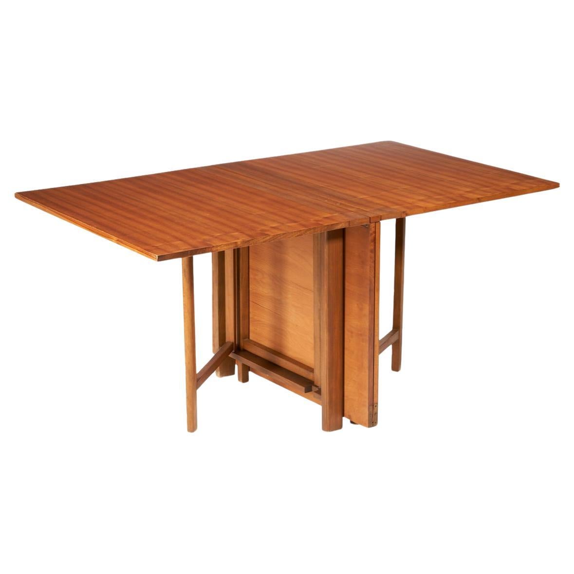Mid-Century Modern Maria folding extension dining table designed by Bruno Mathsson. Table is Teak wood brown finish with brass hardware. Good vintage condition. Table folds down very small to stow away while not using. Made in Sweden. Located in