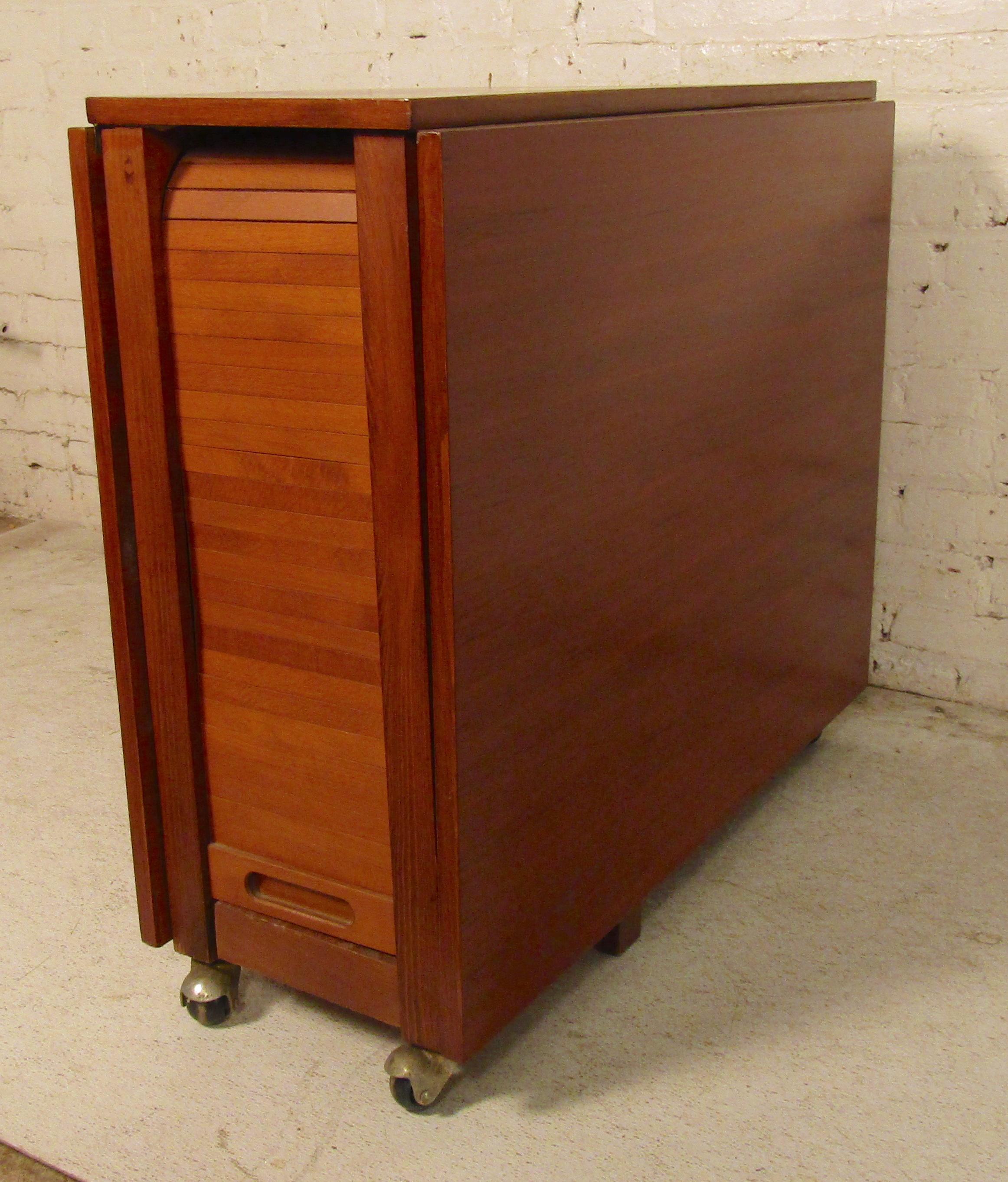 Dining table with two dropping leaves in teak grain, with four slat chairs that sit inside. Set on casters for easy mobility. Table can be used with one or both leaves up.
Measures: Closed: 13
