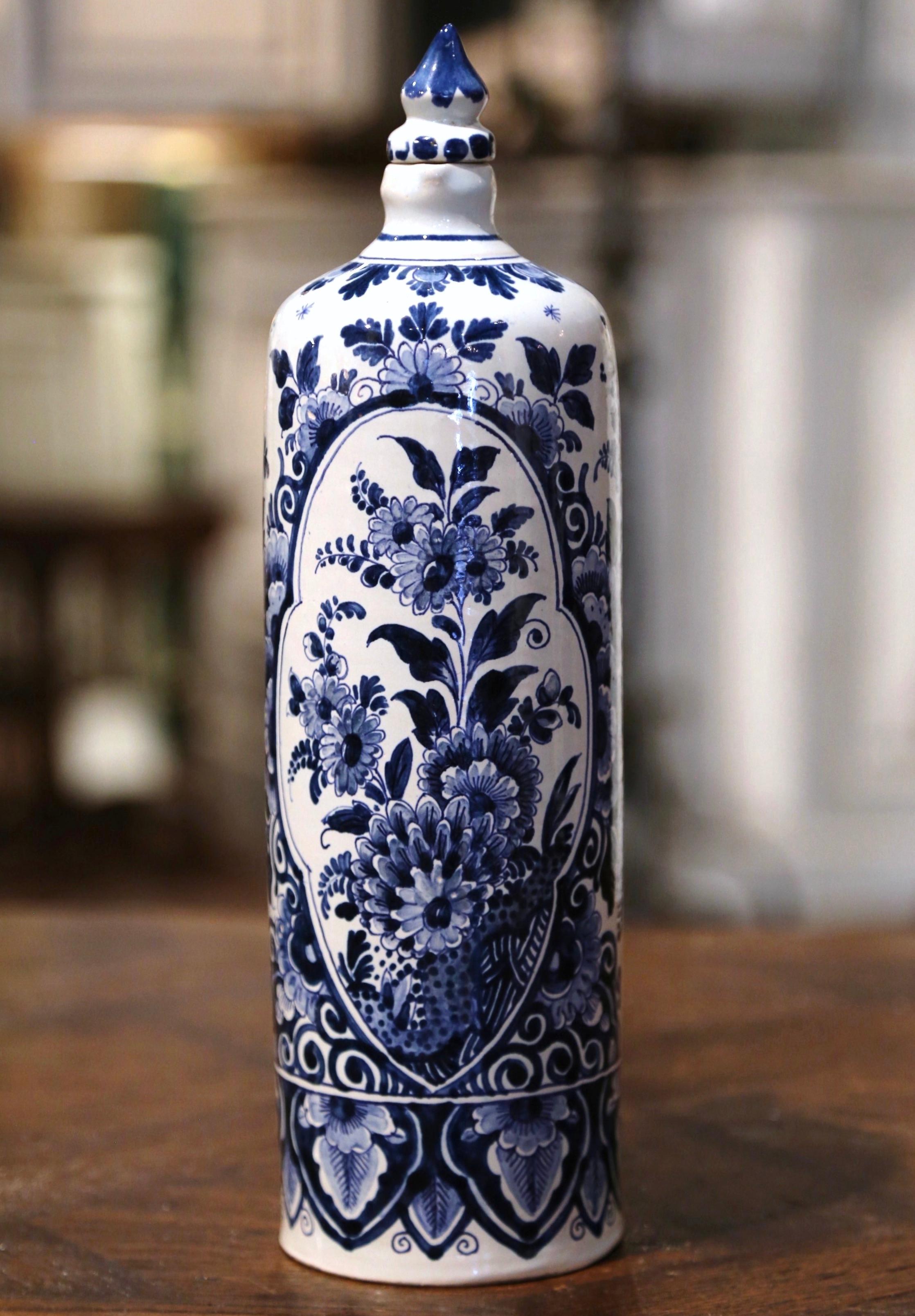 Decorate a shelf or kitchen counter with this elegant antique Delft olive oil container. Crafted in Holland circa 1940, the tall vase with cork top, features an intricate round shape; the vessel is hand painted in the traditional blue and white