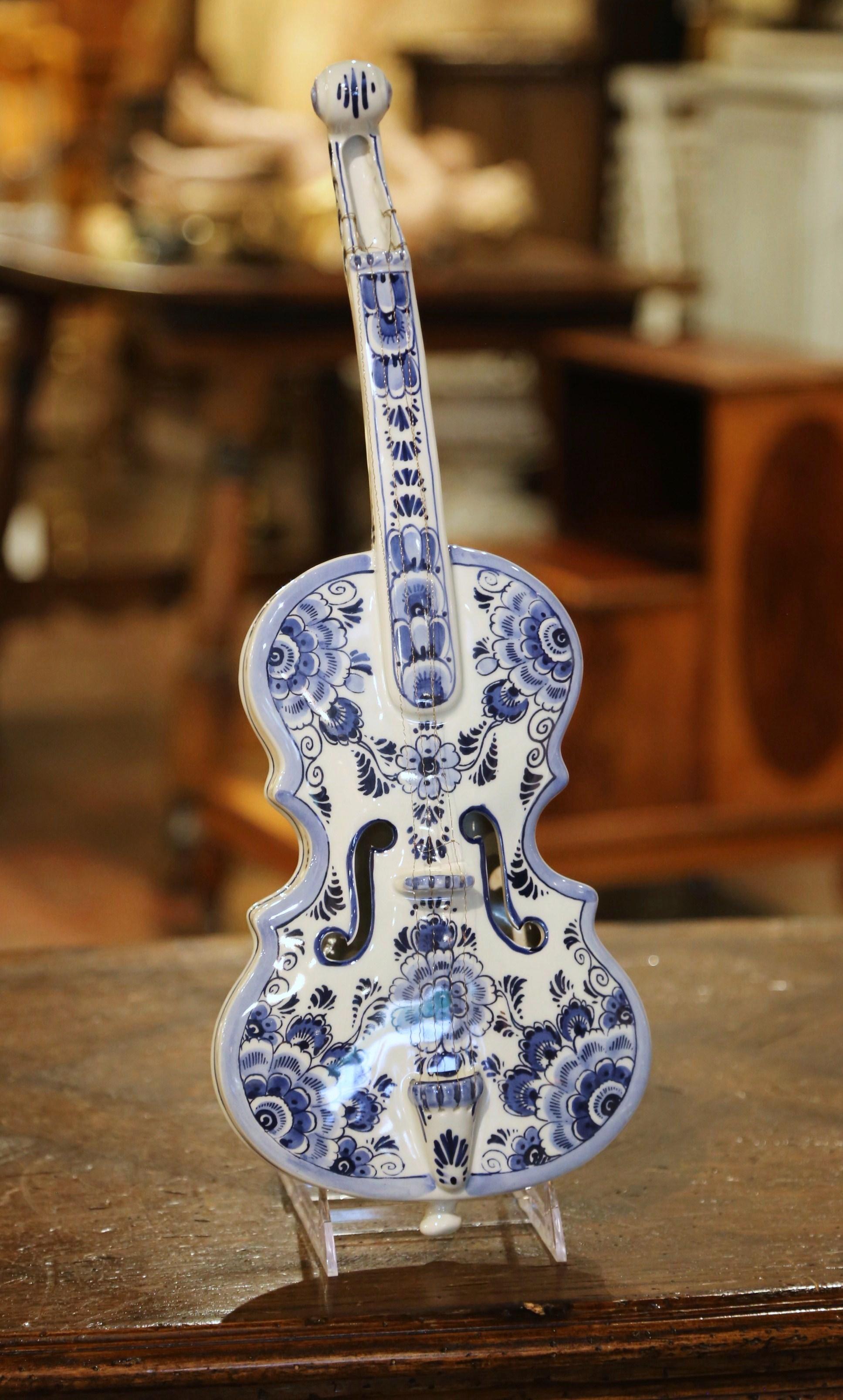Decorate a wall or a shelf with this elegant antique ceramic violin. Crafted in the Netherlands circa 1970,  the colorful faience music instrument features hand painted floral decor in the traditional Delft blue and white palette. The decorative