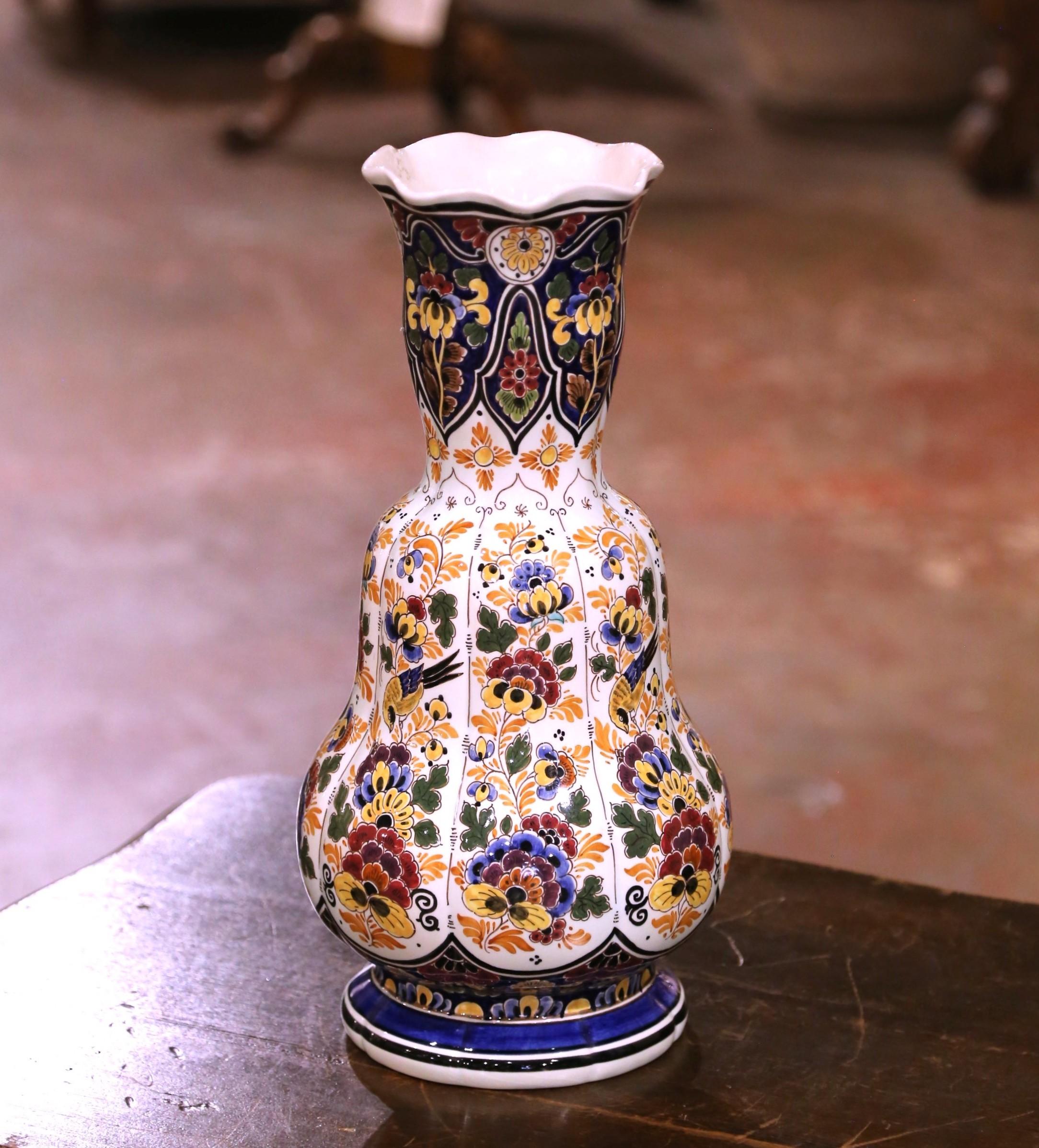 Ajoutez une touche vibrante d'art céramique hollandais à votre collection avec ce vase Delft peint à la main. Produit par la célèbre usine RAM d'Arnhem, en Hollande, vers 1950, ce grand récipient de forme balustre présente un bord richement festonné