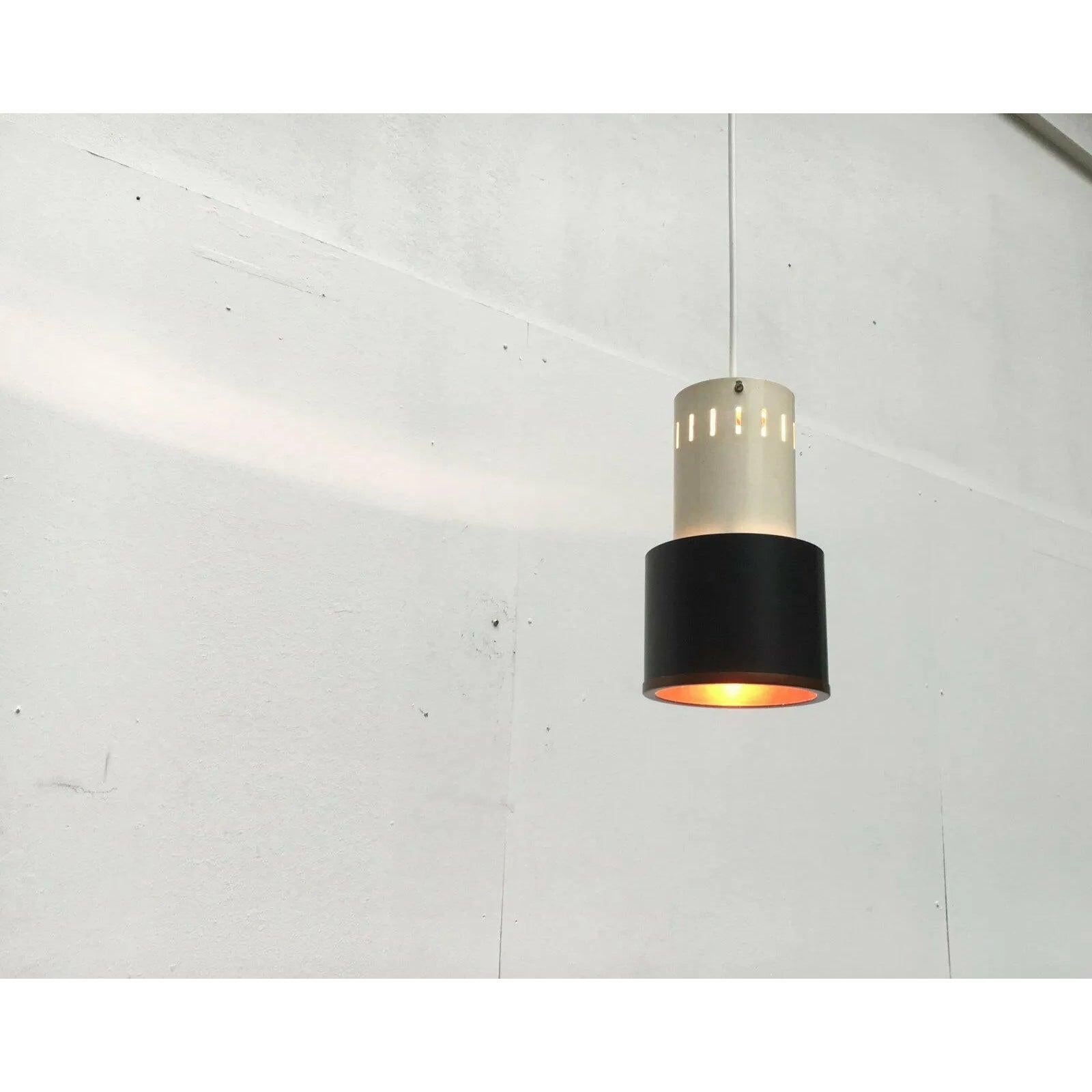 Piccola lampada a sospensione in rame, bianco e nero di Philips basata su un design di Louis Kalff degli anni '50.

Un design semplice e simmetrico con corpi cilindrici come forma predominante. Il contrasto tra il bianco e il nero opaco è