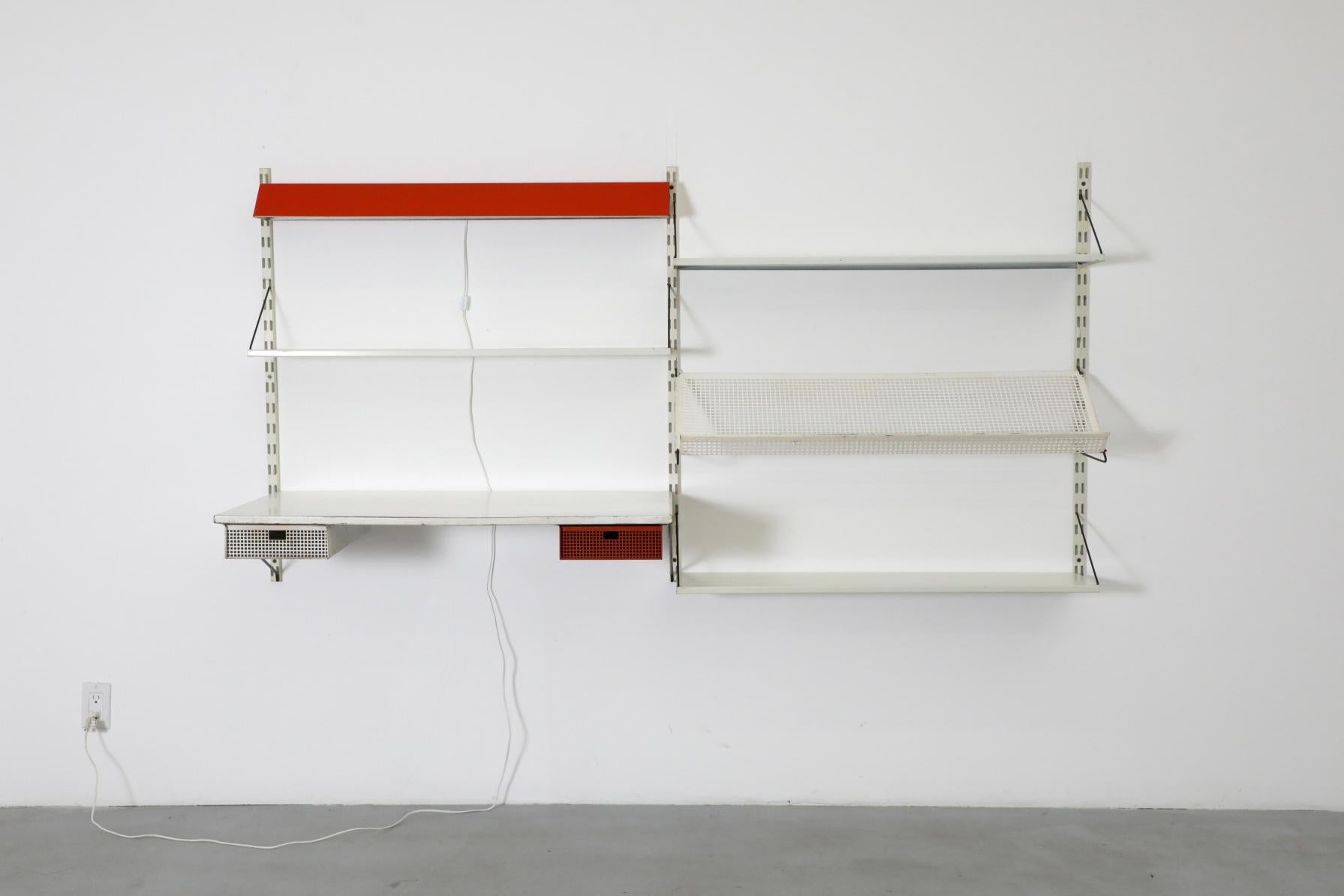 Scaffale da parete in metallo smaltato olandese di metà secolo, Pilastro. Questa unità presenta una scrivania smaltata grigia con cassetti perforati, un portariviste perforato bianco, una luce da tavolo rossa a doppia lampadina e tre ripiani. Ogni