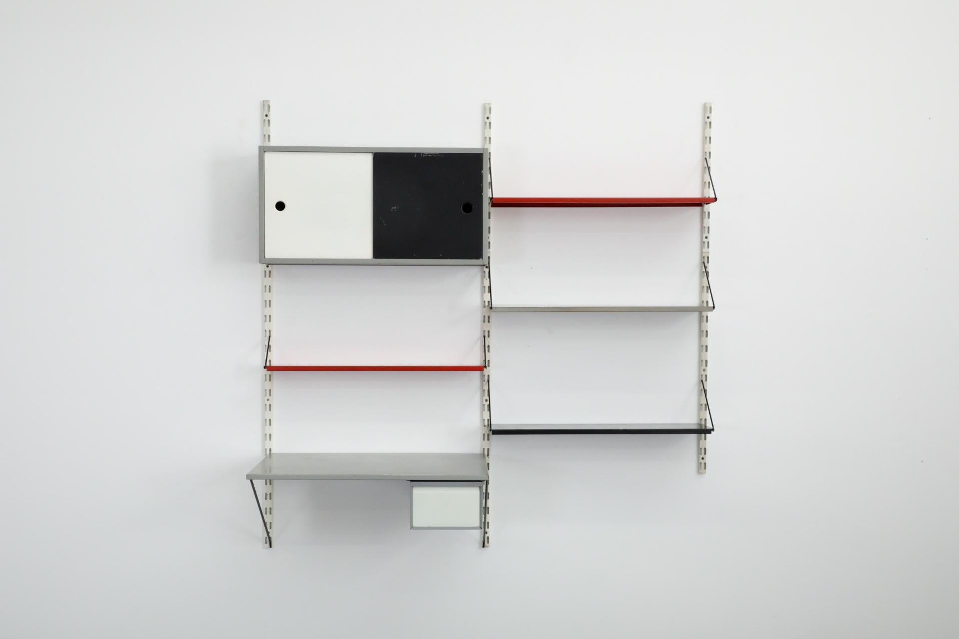 Charming Dutch Mid-Century, Pilastro enameled metal wall unit with desk and upper cabinet. This unit features a gray enameled desk and cabinet with black and white sliding doors, three full size shelves and one mini shelf. The desk has a larger