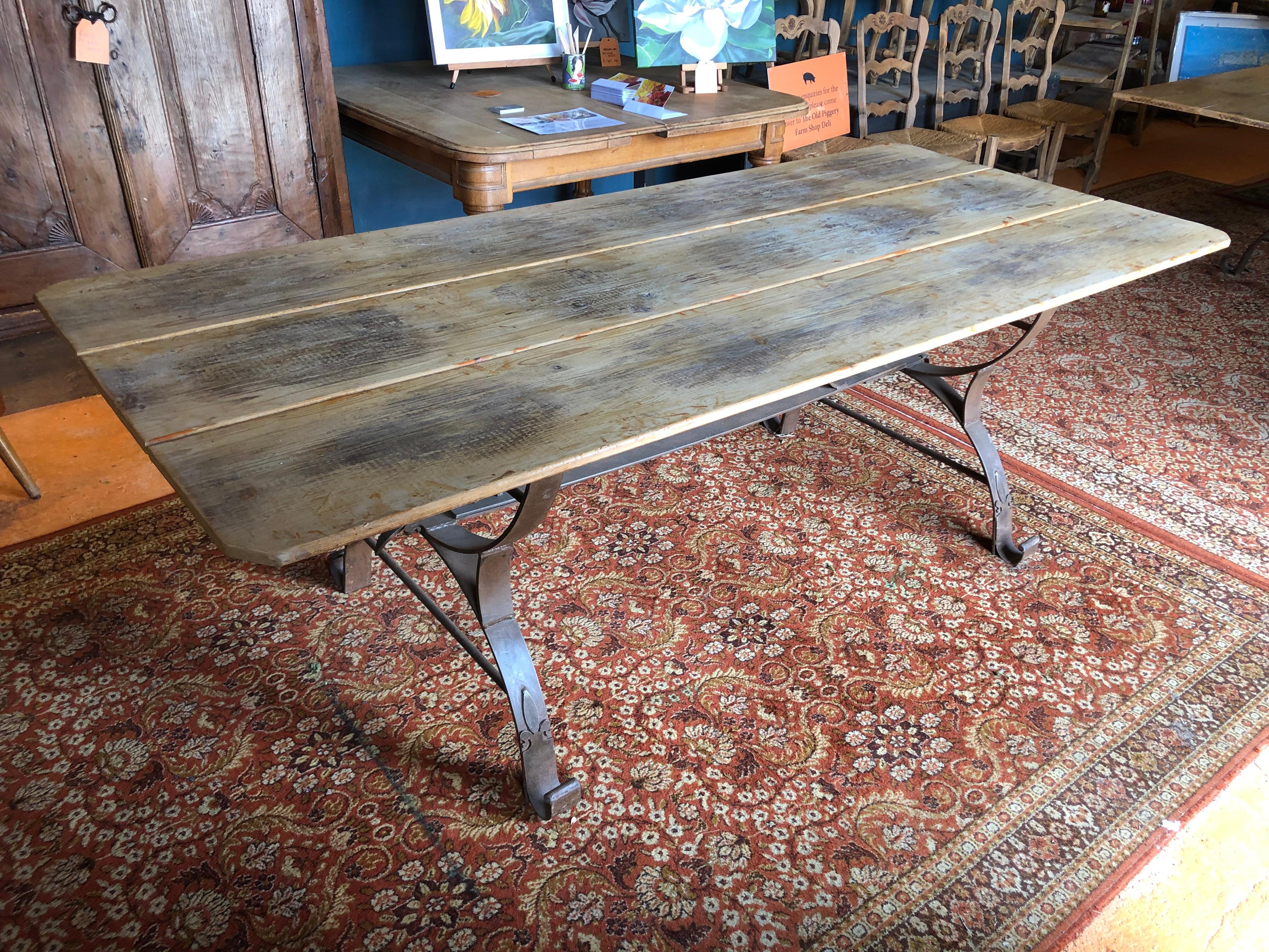 A well-proportioned rustic midcentury Dutch pine dining table with a handmade iron base with fleur-de-lys decoration.

This tabletop was taken from an old gouda cheese factory in Holland. One can still see where the wheels of cheese were left to