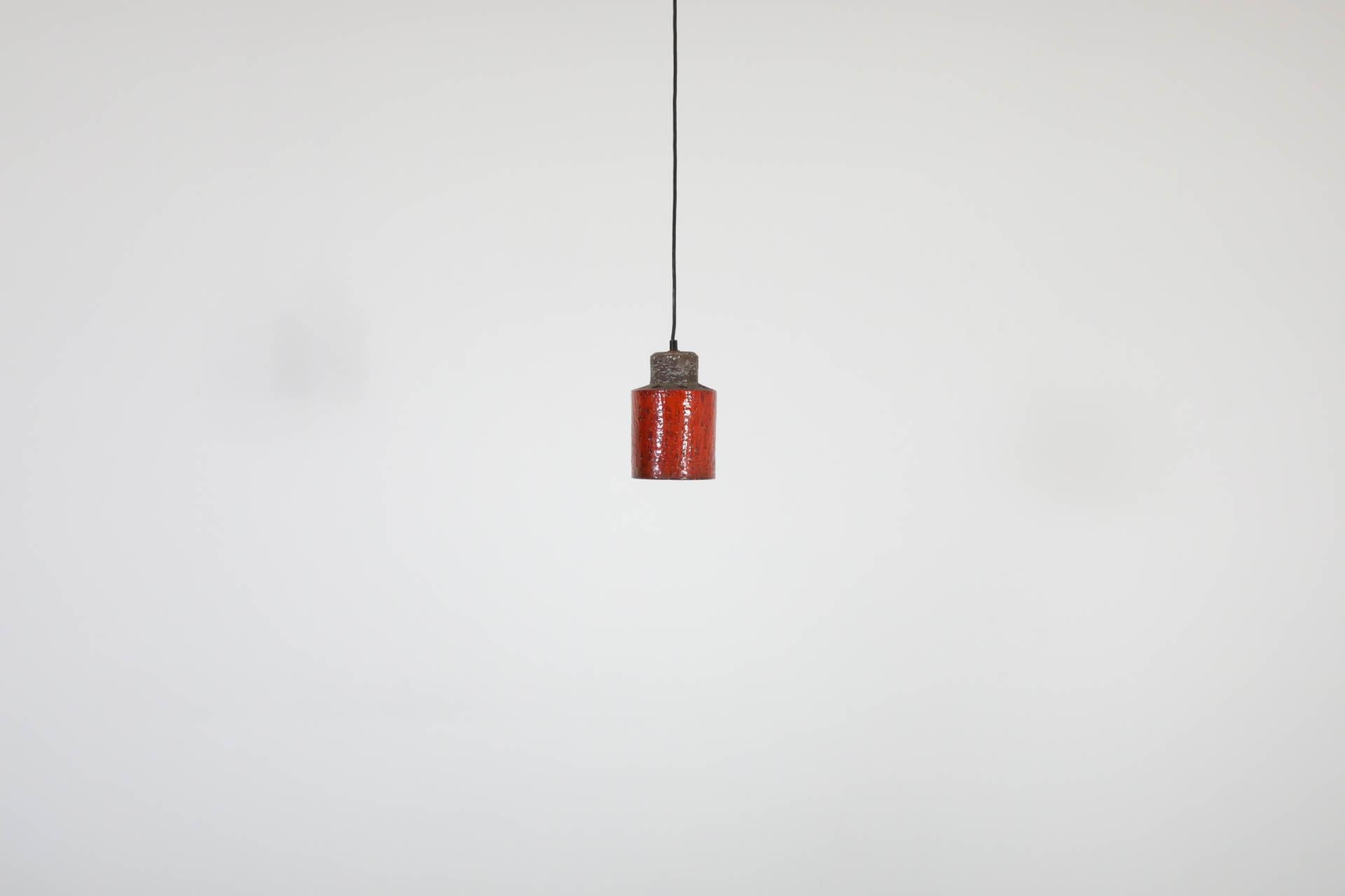 Lampada a sospensione olandese di metà secolo, anni '60, in ceramica rossa, con piccoli ritagli rotondi sulla parte superiore che lasciano trasparire la luce ambientale. Queste perforazioni creano anche un effetto visivo interessante e accattivante