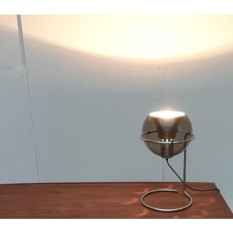 Rare Space Age table lamp with glass ball reflector.

The most striking thing about this lamp is the movable reflector made of tinted glass, which lies on a finely executed foot. The glass light body reveals the inner life, the funnel -like