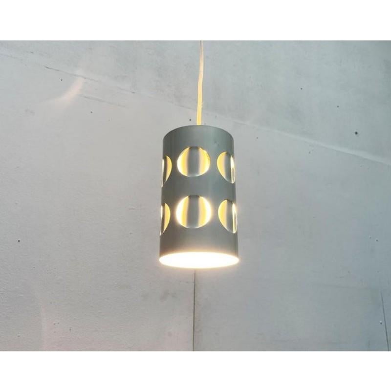 Un design minimaliste. Le corps de la lampe est un simple cylindre. Celui-ci est encore ouvert en haut et en bas afin que la lumière puisse émerger dans les deux sens. La particularité est la perforation au milieu de la lampe. Grands cercles