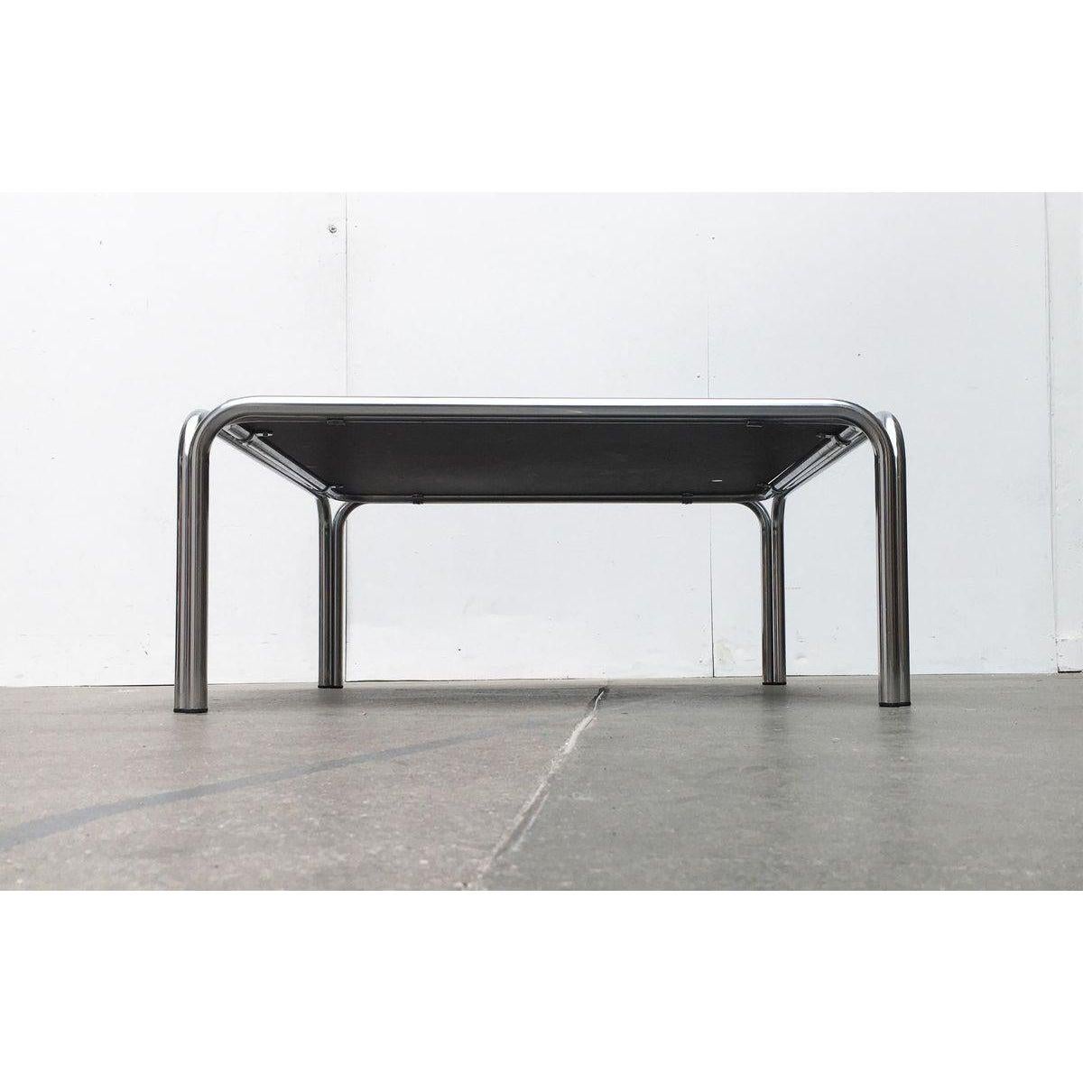Mesa de centro de la empresa holandesa t' Spectrum basada en un diseño de Claire Bataille de la colección de 1969-1974. Aquí en una rara versión con tablero revestido de blanco.

El diseño se basa en los clásicos muebles tubulares de acero de