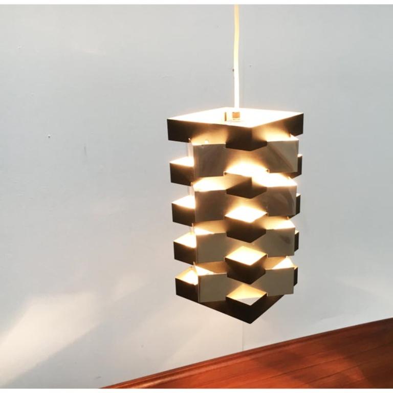Rara lampada a sospensione di Anvia progettata dal designer olandese J.J.M. Hoogervorst negli anni '60.

La lampada è caratterizzata da una geometria chiara. La forma di base consiste in due corpi rettangolari ruotati di 45 gradi. I corpi sono