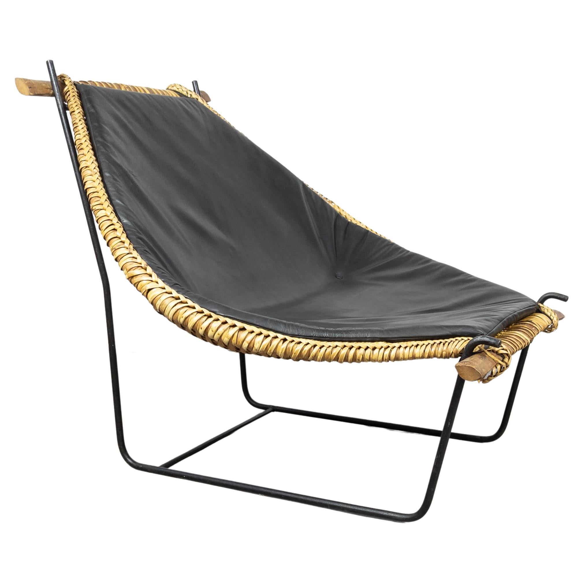 This unique lounge chair was designed in 1953 by John Risley for Ficks Reed. A combination of braiding and weaving techniques were used to create the rattan 'basket,' which is anchored at both top and bottom by carved bamboo rails. This basket seat