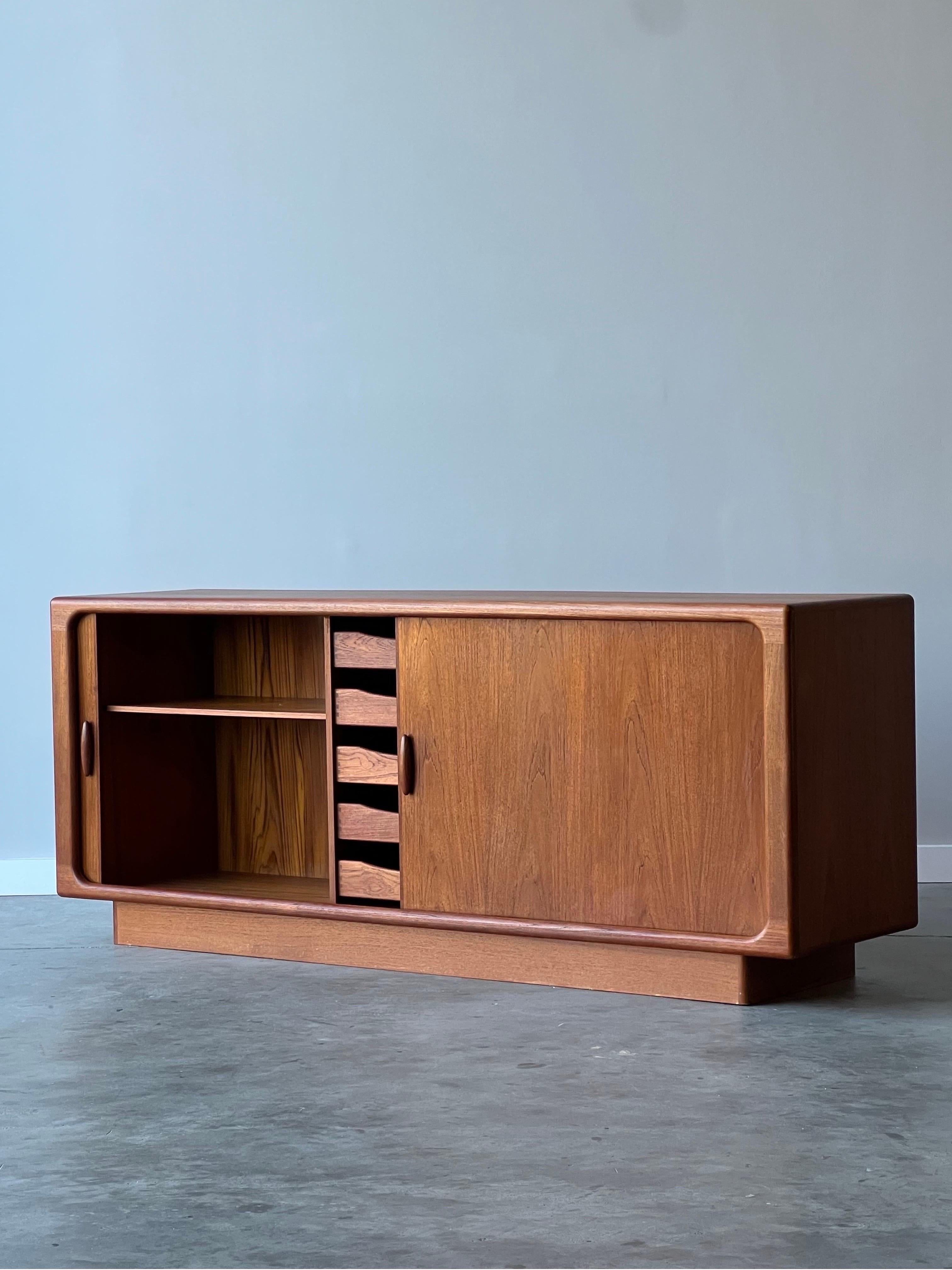 Happy to offer this wonderful 1960’s Danish teak credenza by Dyrlund. Bursting with character and sleek design. Plenty of adjustable storage space and superb sliding tambour doors. Nice rounded features and robust teak grain throughout. Sculptural