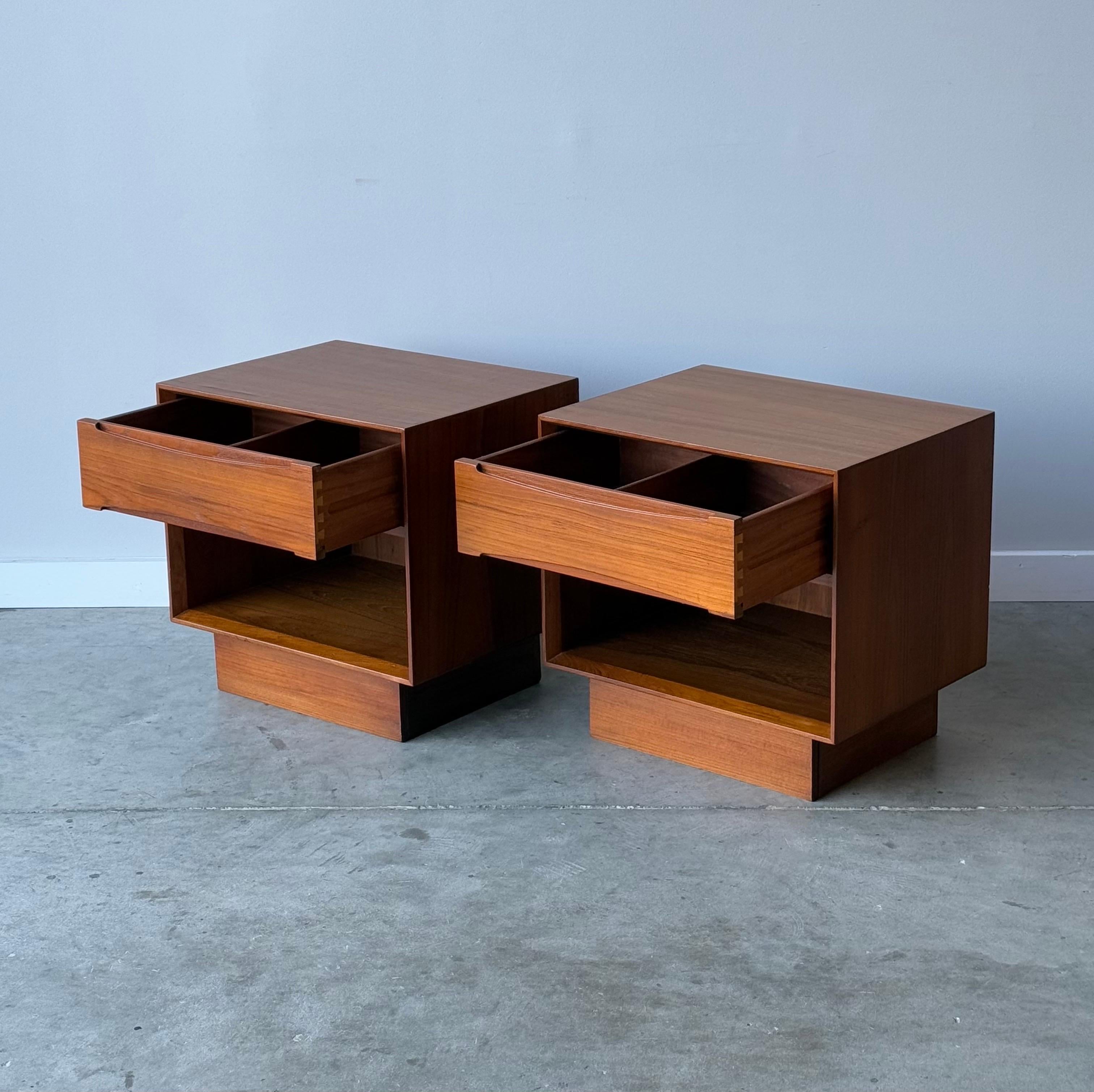 Mid-century teak nightstands made by Dyrlund. Made Denmark circa 1960s. Cube in shape on a sturdy plinth base. Featuring one single smooth sliding drawer with internal divider. Drawers have inset carved handles for easy opening and add wonderful
