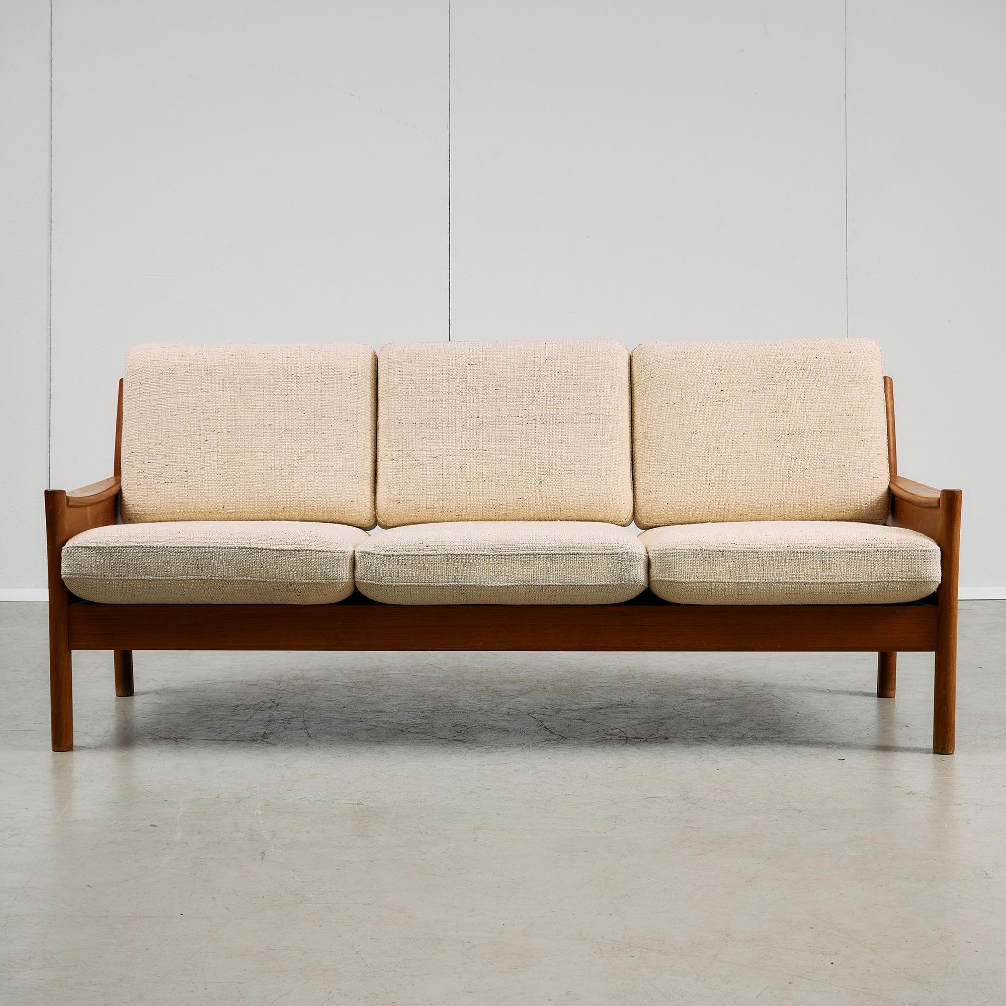 Made by Danish maker Dyrlund, this three-seater sofa is crafted from solid teak and built with the kind of careful joinery and attention to detail the brand is known for. The frame features gently curved armrests, adding a softer line to the strong,