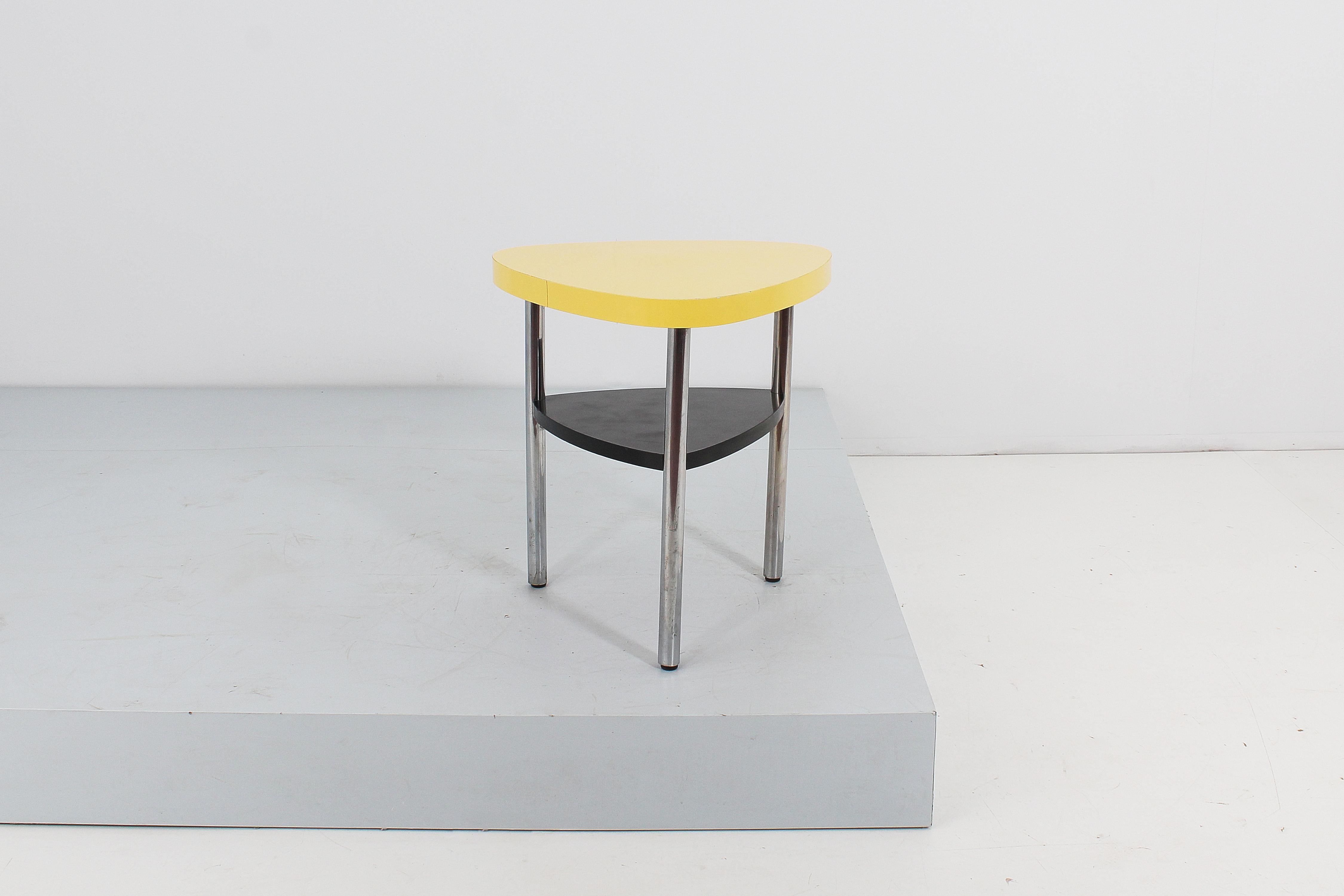 Triangular shaped coffee table with double wooden shelf covered in yellow (upper level) and black (lower level) Formica. Three tubular legs in chromed steel. In the style of Ettore Sottsass, Italian production from the 50s.
Wear consistent with age