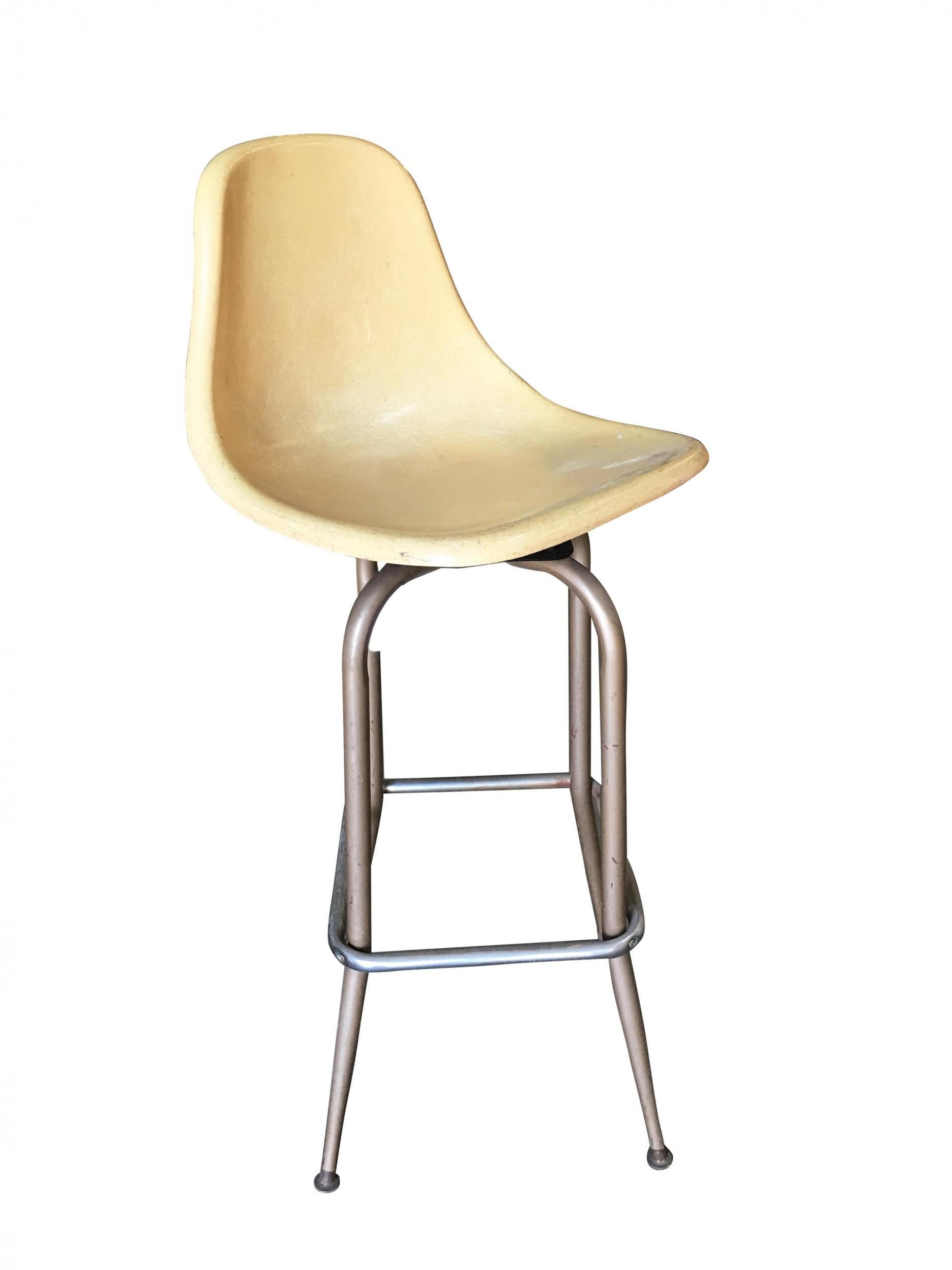 This pair of vintage midcentury fiberglass shell seat swivel bar stools feature a retro charm. The bucket seats are made of durable fiberglass, exuding classic elegance. The chrome steel base ensures stability and adds a touch of modernity. These