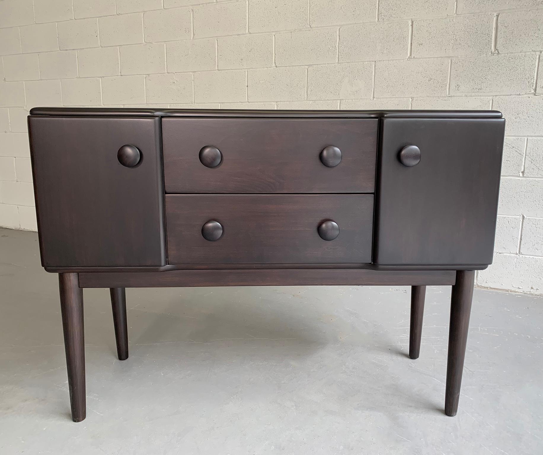 Mid-Century Modern, solid ebonized maple, sideboard, credenza or console by Heywood Wakefield features center drawers and side cabinets that measure 14.5 inches height with distinct round handles and tapered legs. The cabinet height itself is 19
