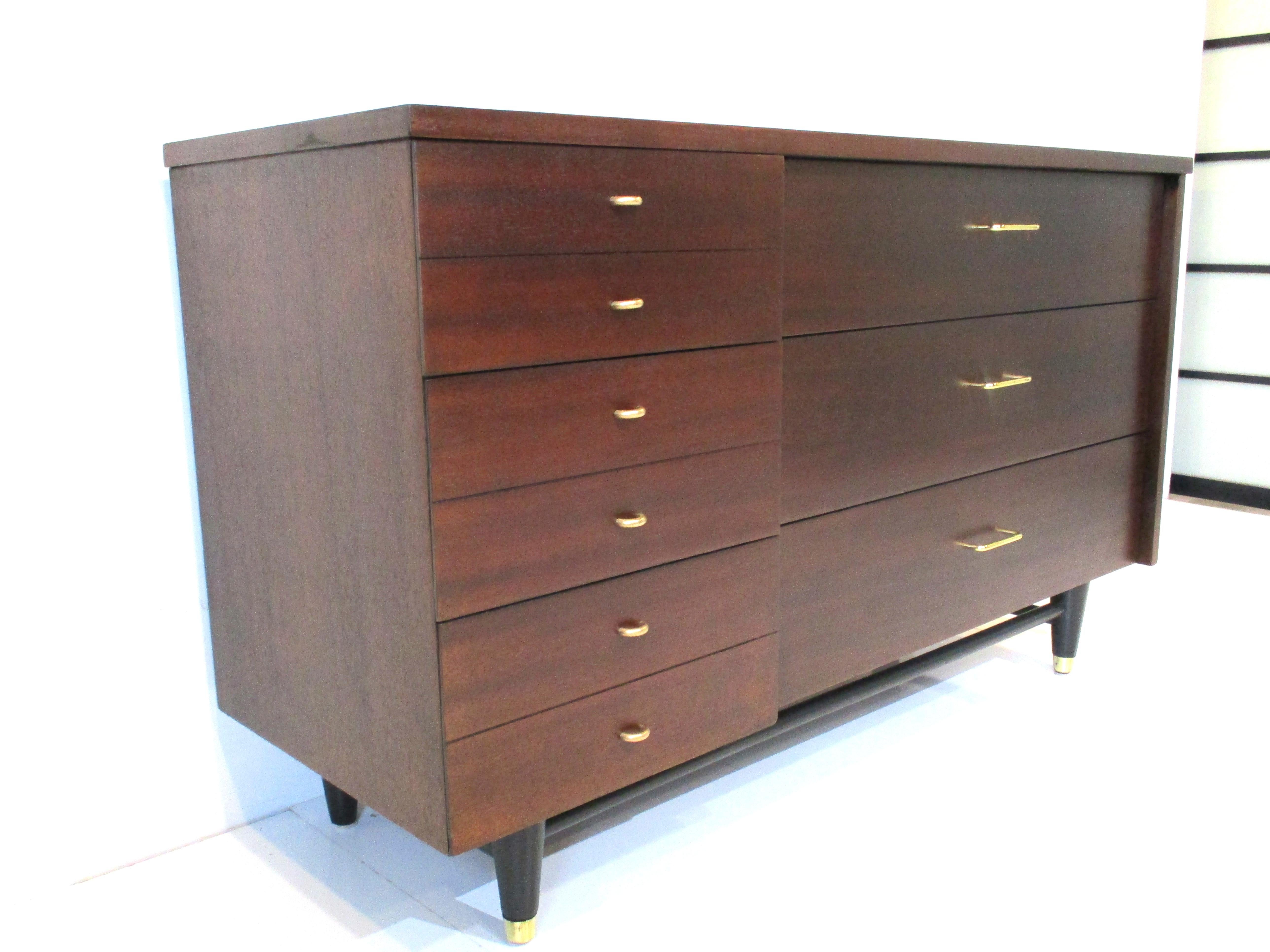 A ebony toned six drawer dresser chest with three smaller ones to the left side and three large drawers to the other . Having brass pulls and brass capped front legs with the stretchers and conical upper legs in a satin black finish.