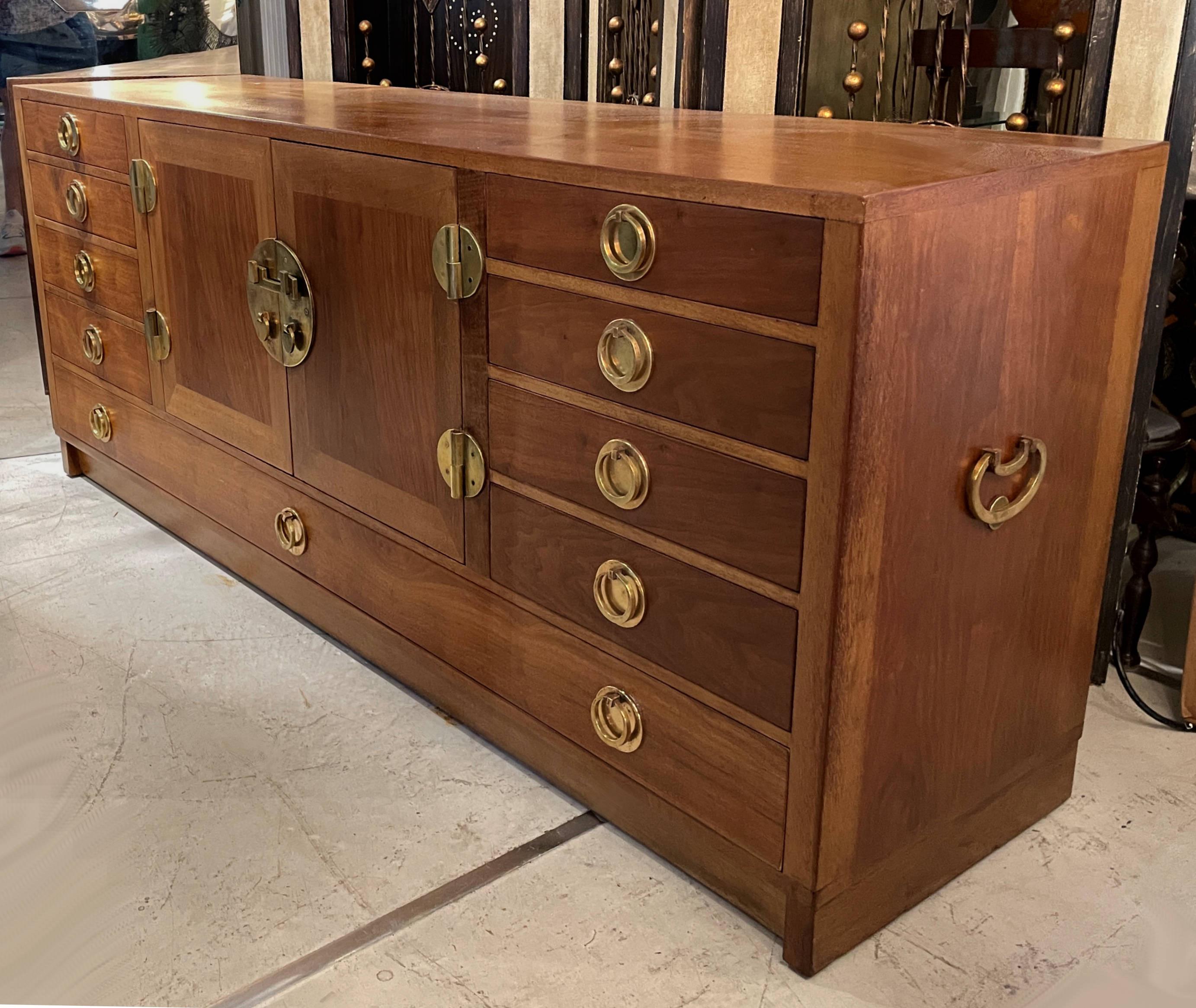 A warm Edward Wormley for Dunbar credenza in a beautiful mahogany wood with solid brass hardware. There are nine drawers with center cabinet. The quality of the construction is very sturdy and of fine materials in very good condition.