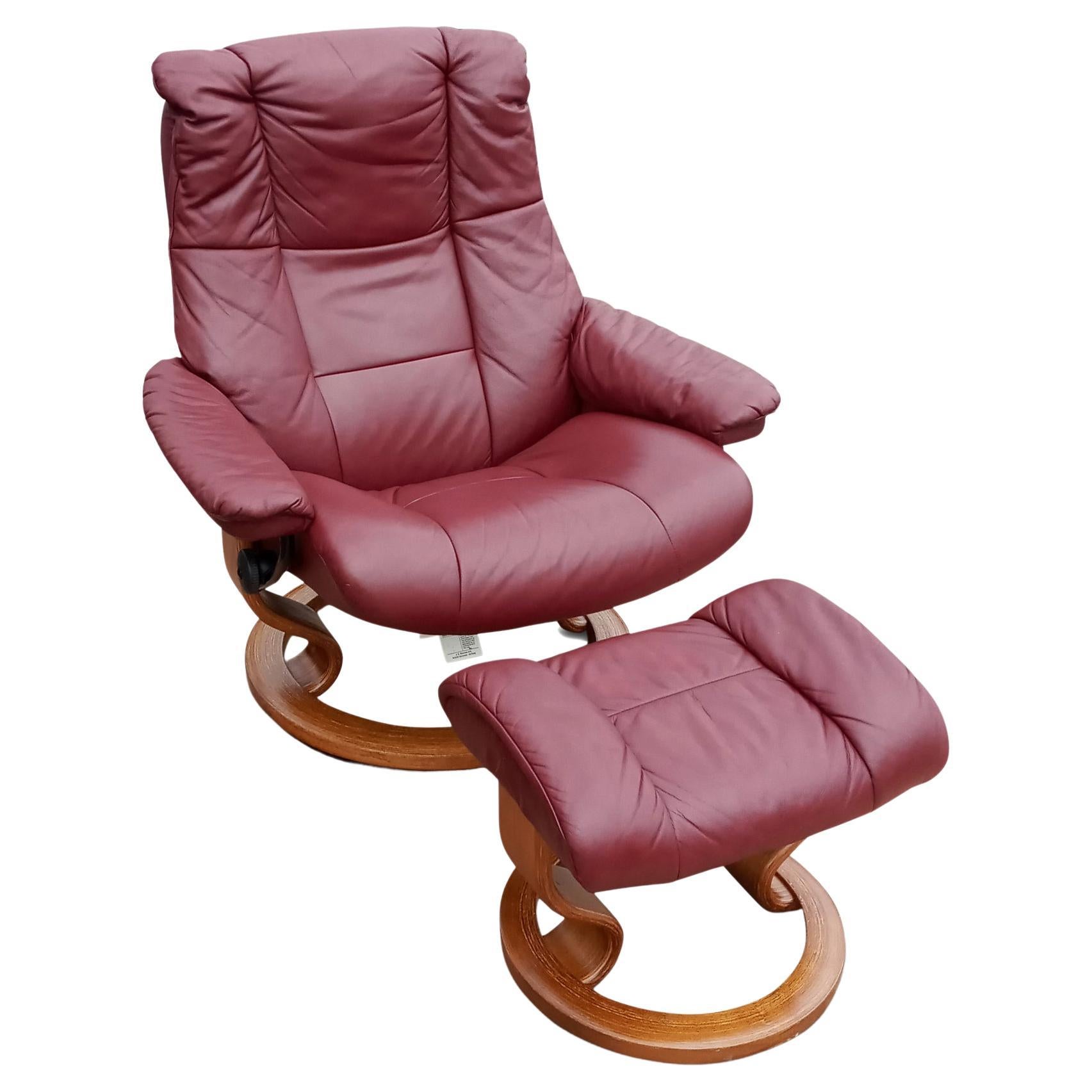 A Scandinavian style recliner and ottoman by Ekornes, their Stressless brand. With teak wood bases and metal frame and genuine leather upholstery, this is a comfortable burgundy color leather recliner on a round teak wood base that swivels 360